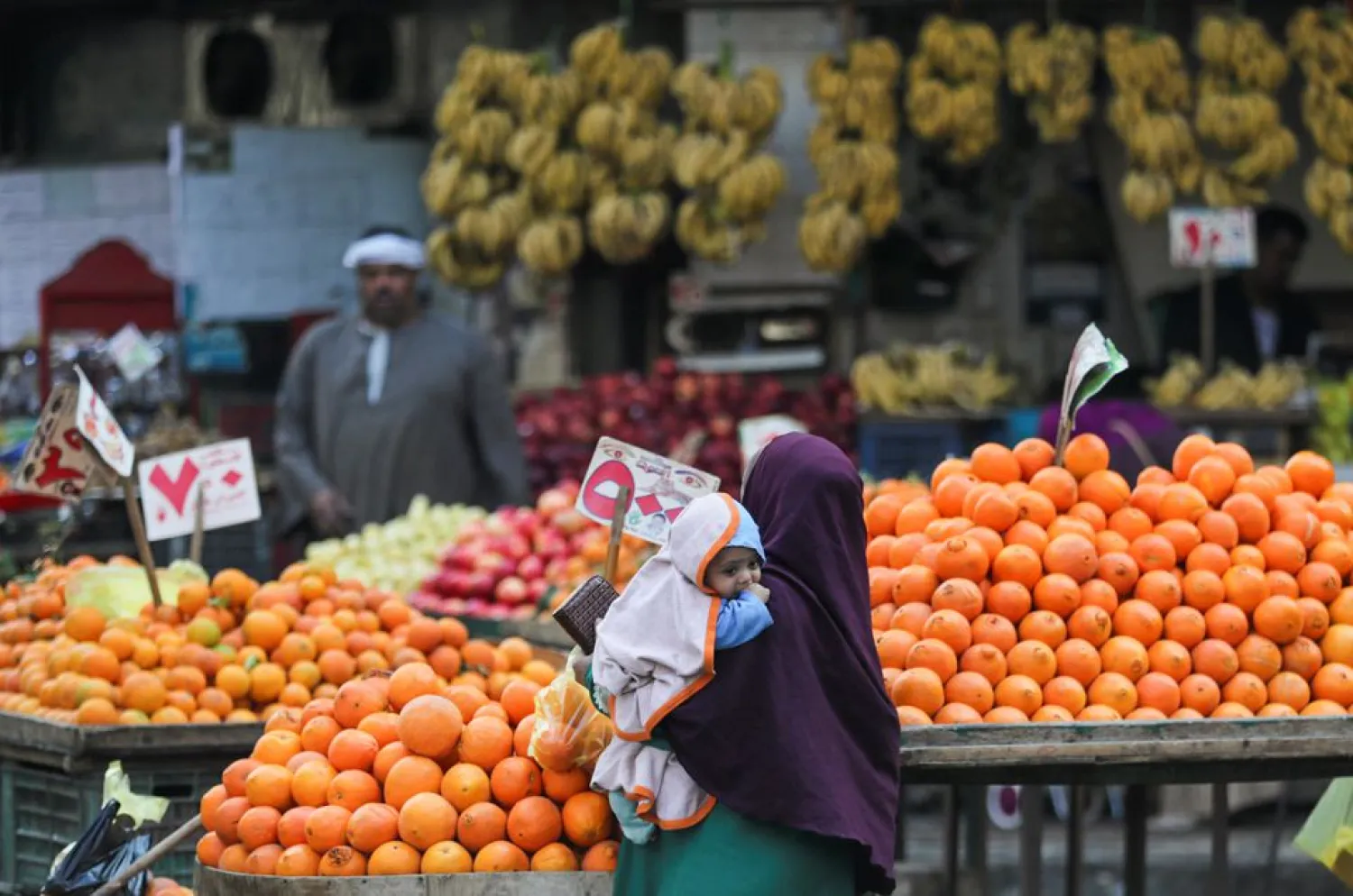 A woman holding her baby shops at a vegetable market in Cairo (Reuters)
