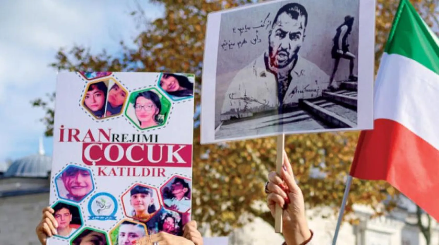 26 Kasım 2022 cumartesi İstanbul’da İranlı kadınları desteklemek için düzenlenen bir yürüyüş sırasında İranlı protestolarda rapçi Toomaj Salehi ve çocukların fotoğraflarını taşıyan insanlar (AFP)