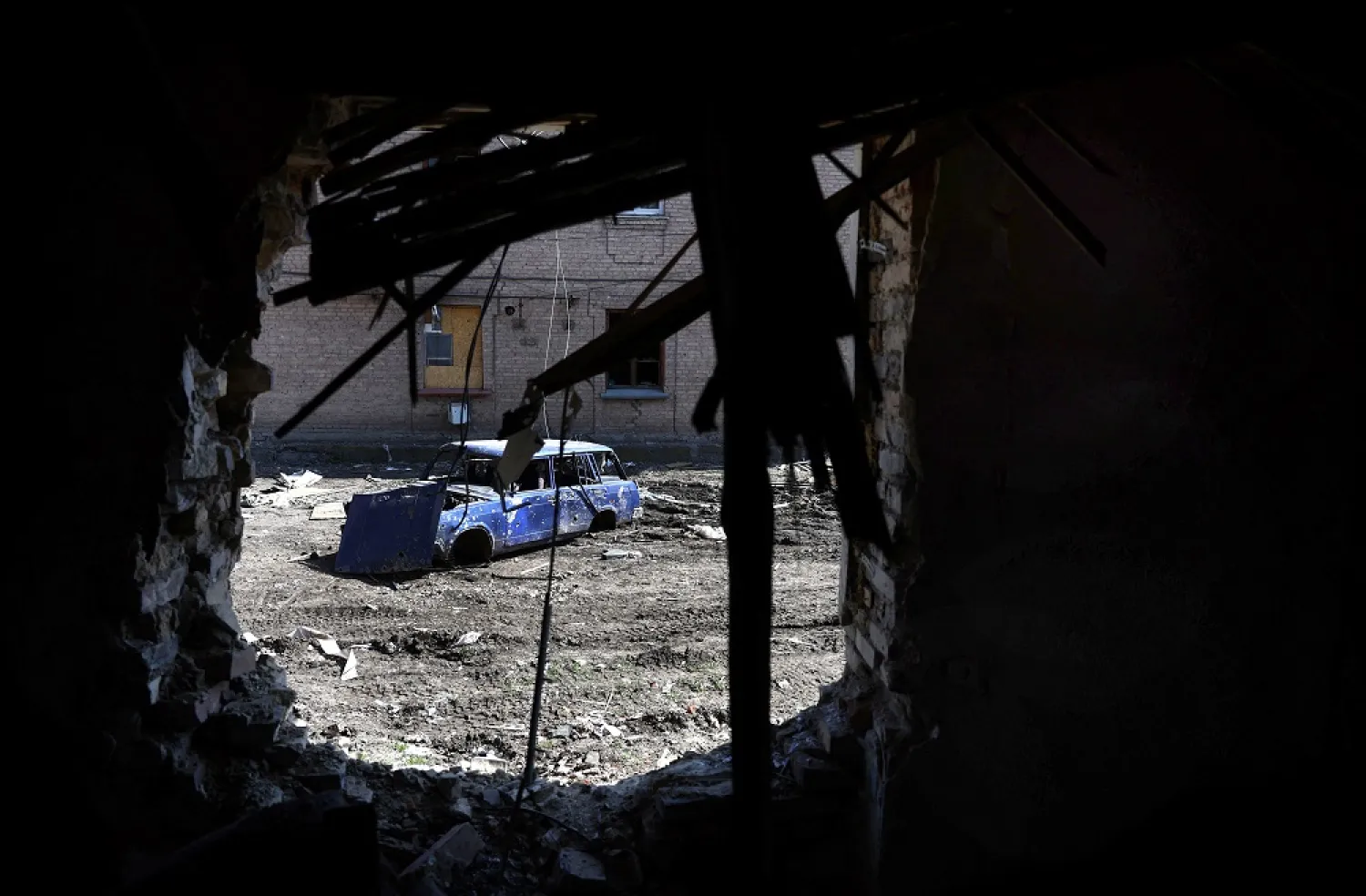 A vehicle, destroyed from recent shelling, is seen through the smashed wall of a residential building during heavy fighting at the frontline of Bakhmut and Chasiv Yar, in Chasiv Yar, Ukraine, April 10, 2023. (Reuters)