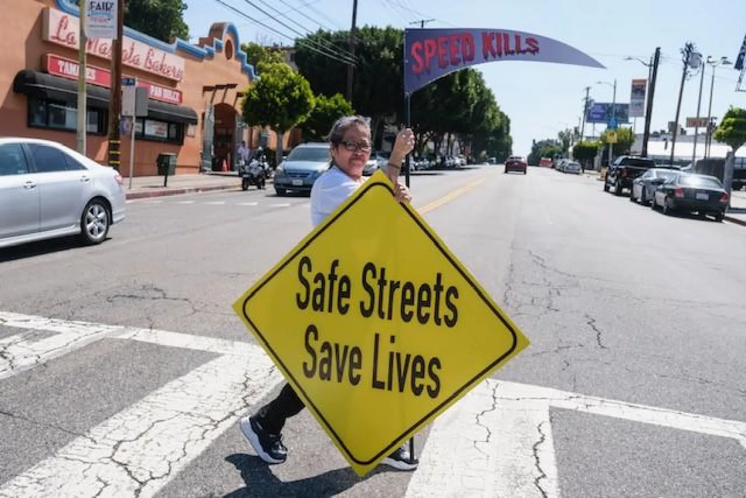 امرأة تحمل لافتة تدعو المواطنين إلى عدم القيادة بسرعة (د.ب.أ)