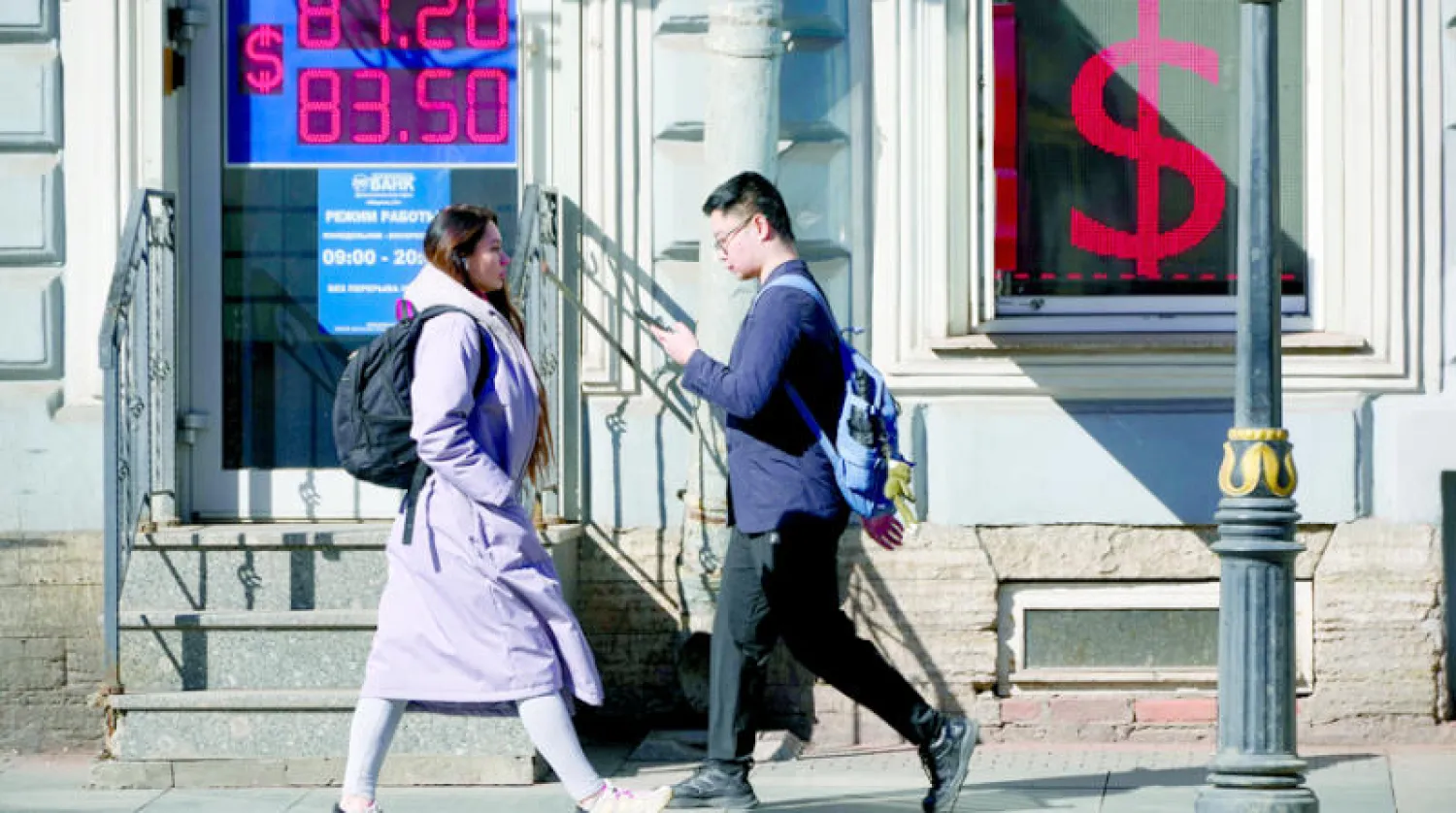 مارة في أحد شوارع العاصمة الروسية موسكو يسيرون أمام محل للصرافة (أ.ب)