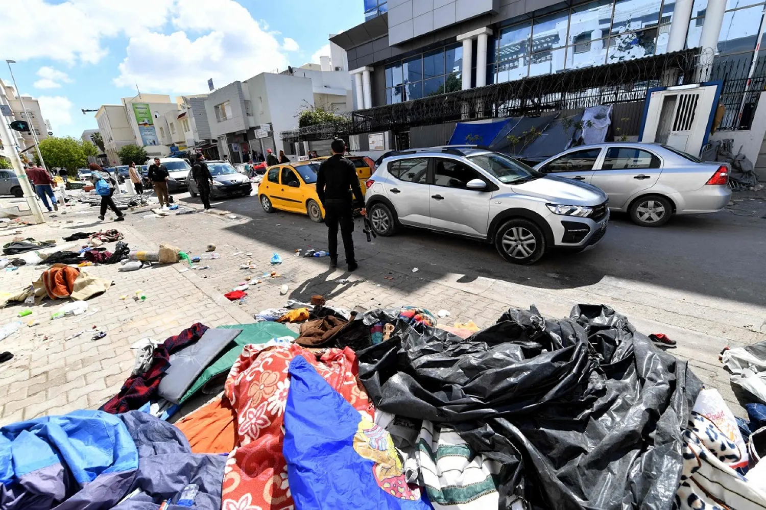 Tents and belongings of migrants are scattered in front of the UNHCR headquarters in Tunis after Tunisian police dismantled a camp for refugees from sub-Saharan African countries, on April 11, 2023. (AFP) 