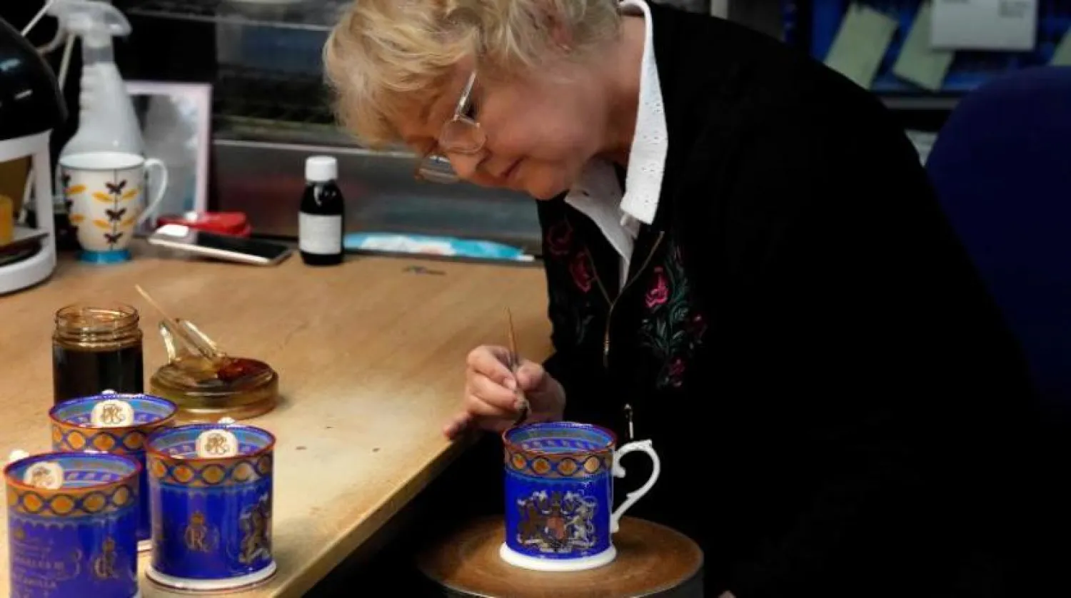A worker paints the finish on official chinaware in a pottery in Stoke on Trent, Thursday, April 13, 2023. A range of official chinaware produced in Stoke-on-Trent by Royal Collection Trust, a department of the Royal Household, will go on sale on Friday, April 14 to commemorate the upcoming Coronation on May 6, 2023. (AP Photo/Frank Augstein, pool)
