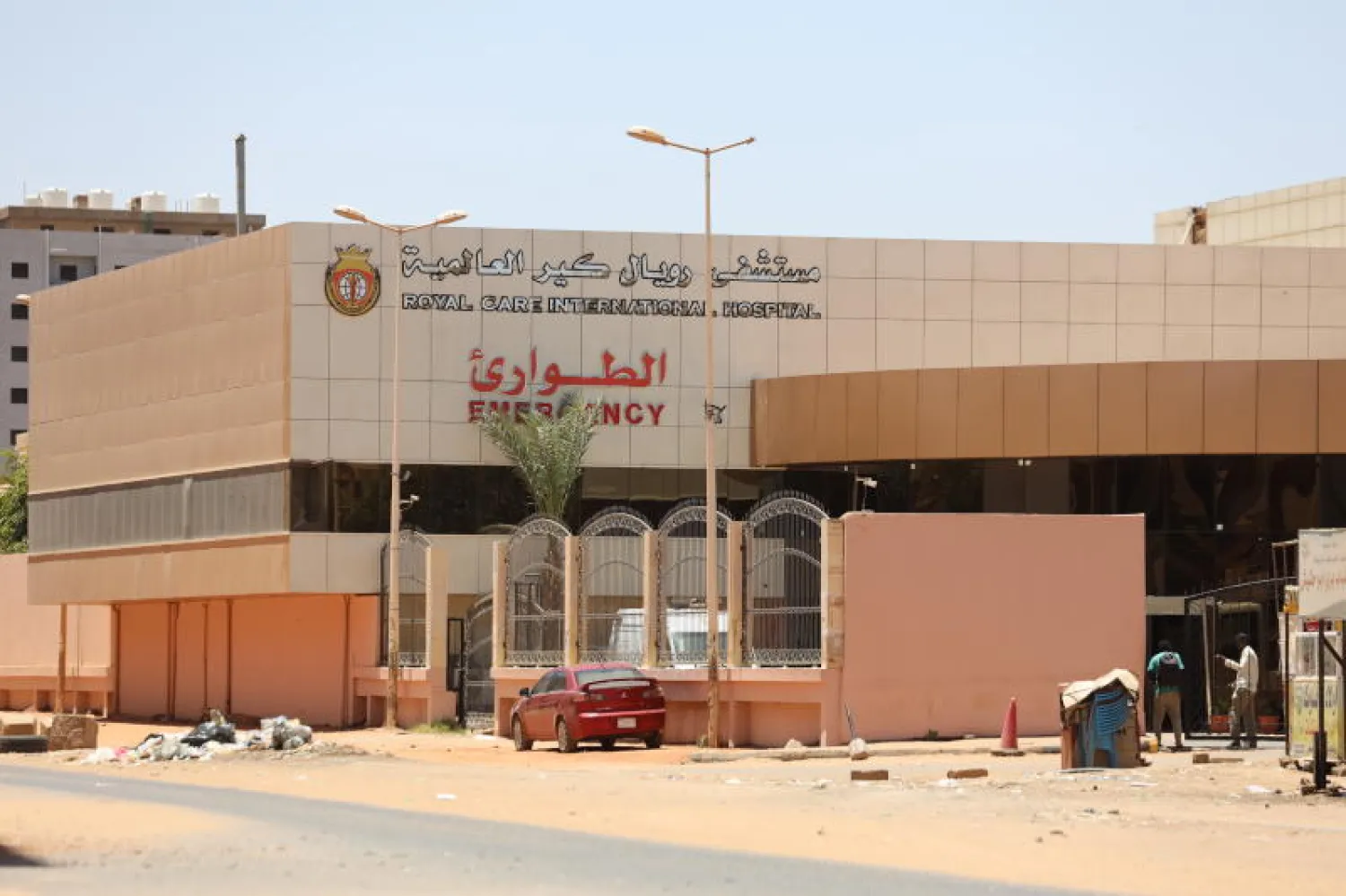 مواطنون سودانيون يقفون أمام مدخل أحد المستشفيات وسط الاشتباكات الدائرة في الخرطوم (إ.ب.أ)