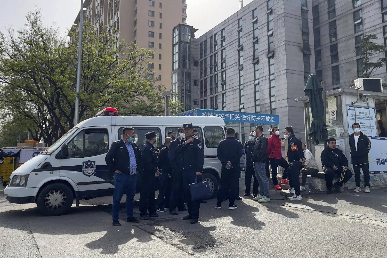 Police officers and security guards gather outside the barricaded hospital following a fire at a hospital in Beijing, Wednesday, April 19, 2023. (AP Photo/Andy Wong)
