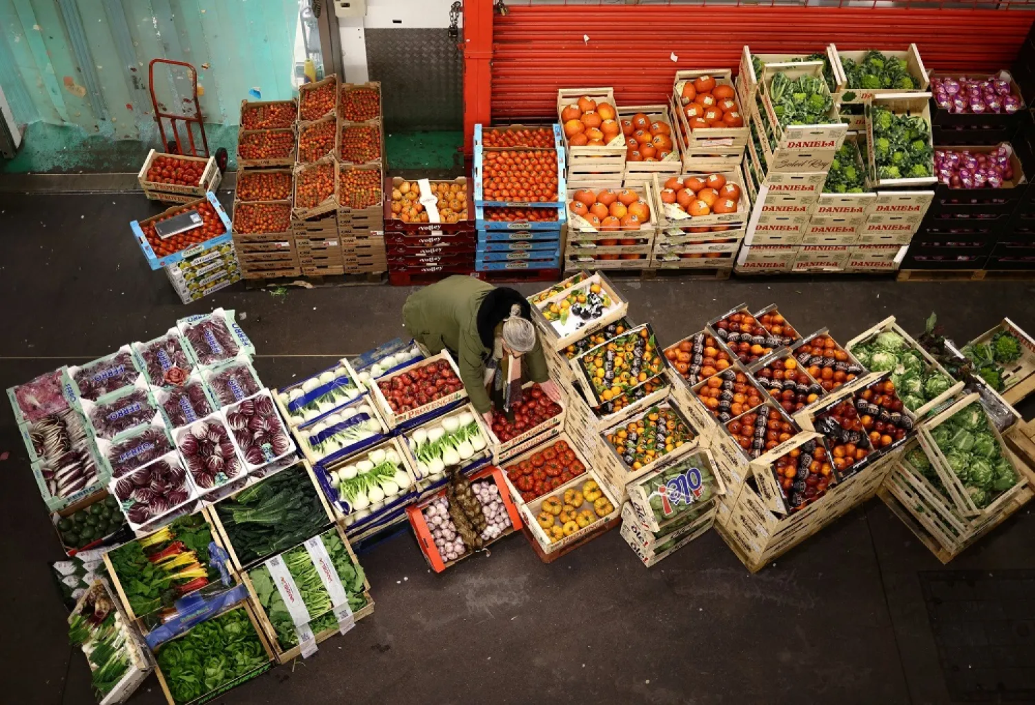A person carries a box of tomatoes during early morning business hours at New Covent Garden Market in London, Britain, March 9, 2023. (Reuters)