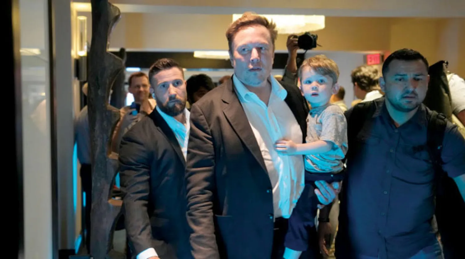 ماسك يحمل طفلا بعد إلقائه كلمة في مؤتمر بفلوريدا الثلاثاء (أ.ب)