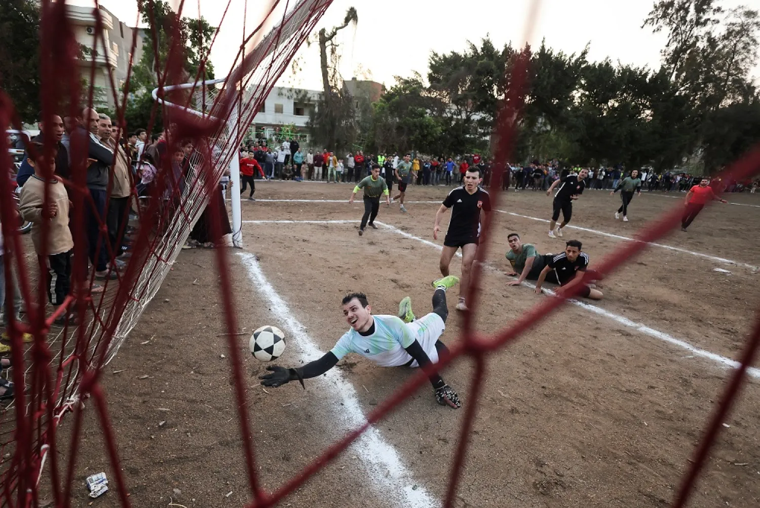 A goalkeeper tries to catch the ball during the annual Ramadan football tournament match on a dirt field at the Kafr Abd al Mu'min village before an Iftar (breaking fast) meal during the holy month of Ramadan in Dikirnis, Egypt April 13, 2023. (Reuters)