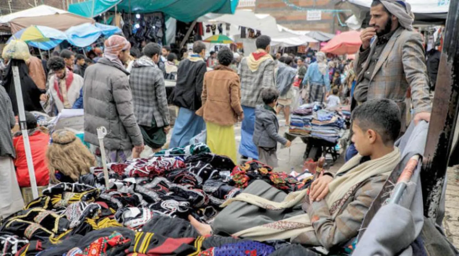 A child sits next to a merchant selling clothes in a market in central Sanaa. (AFP) 