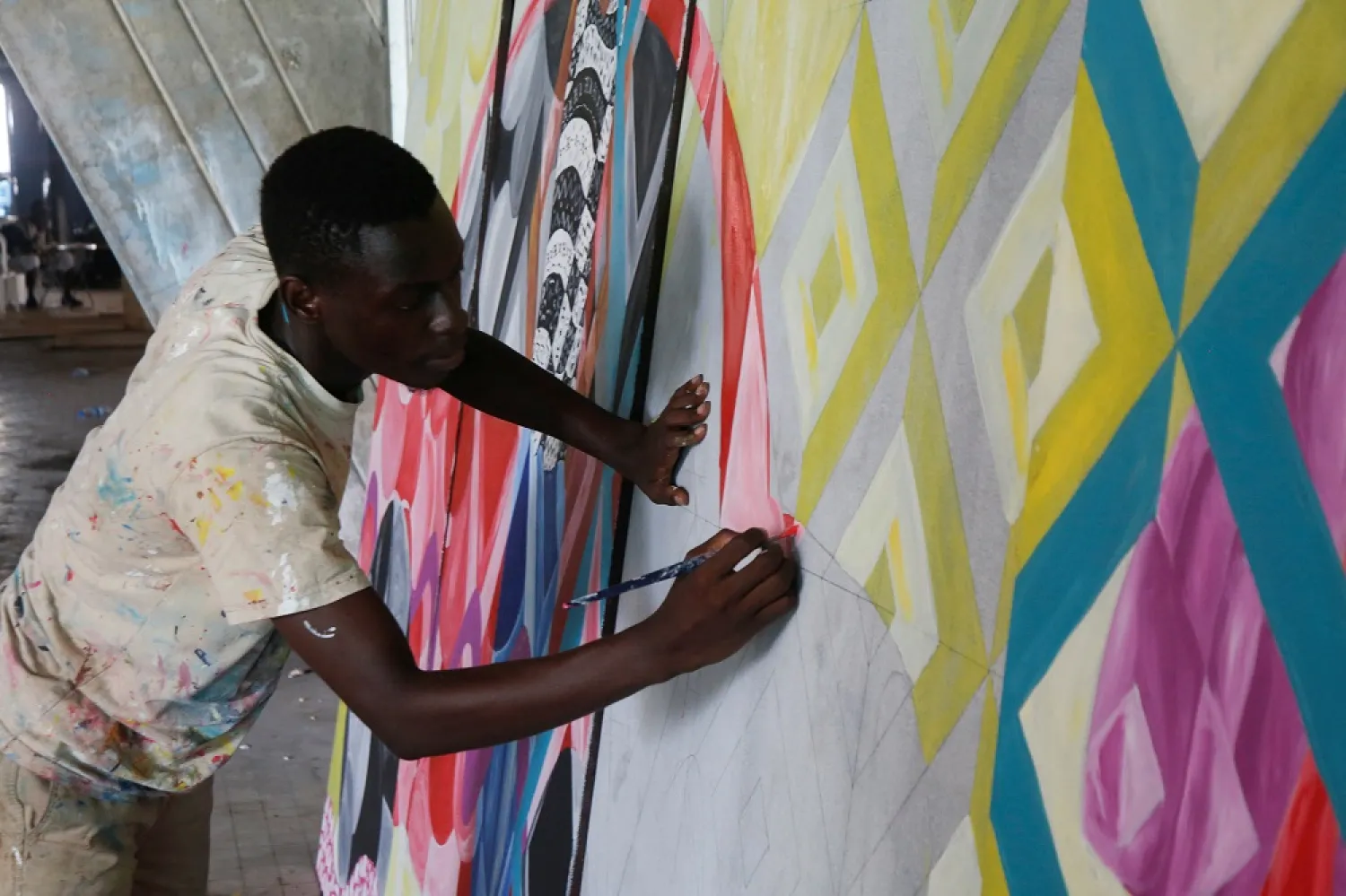 An Ivorian art student works on a painting which will be pasted on a facade of the "Pyramid", the emblematic tower of the Ivorian capital built in the 1970s and has fallen into disuse for twenty years, in Abidjan, Ivory Coast, April 19, 2023. (Reuters)