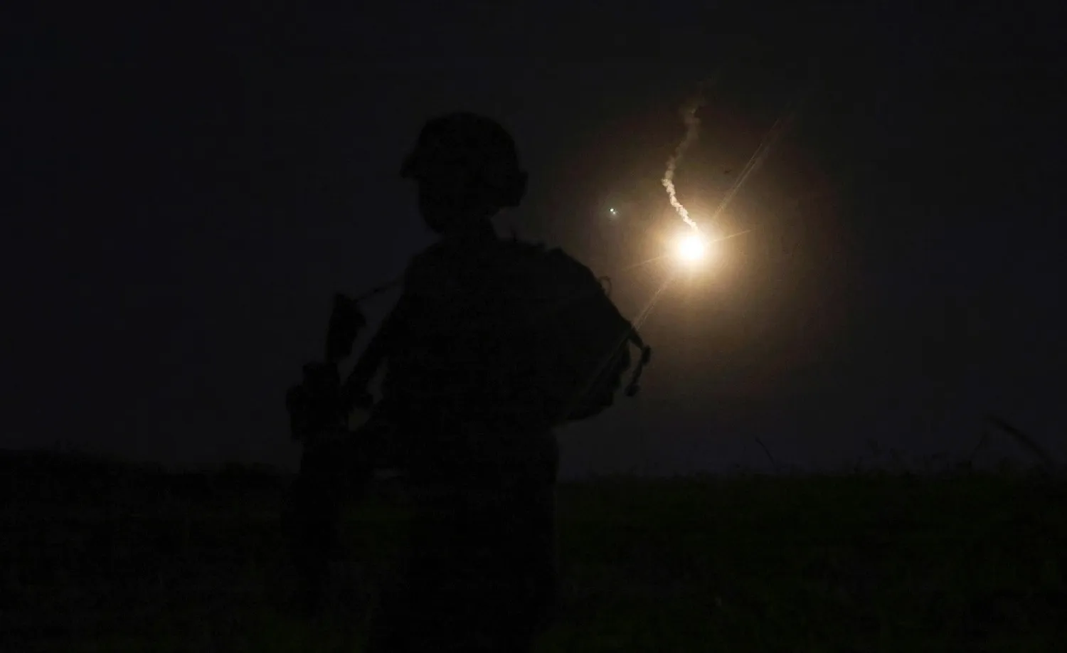 The silhouette of an Israeli soldier is outlined in the sky by a flare fired to search for a rocket that landed near Kibbutz Meitsar in the Israeli- occupied Golan Heights, April 9, 2023. (AFP)