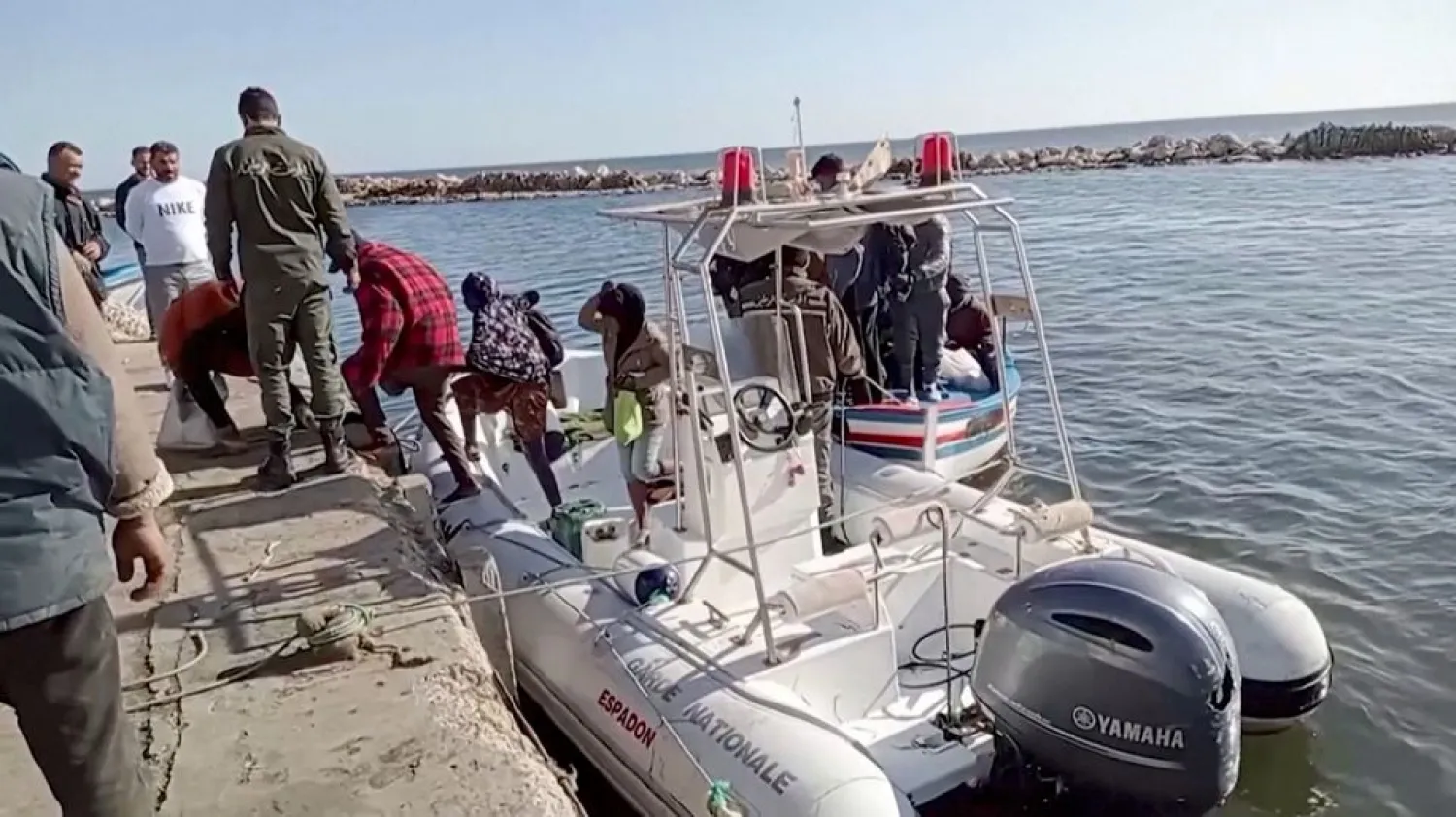 A Tunisian national coast guard helps migrants to get off a rescue boat in Jbeniana, Safx, Tunisia April 23, 2022, in this screen grab taken from a handout video Wahid Dahech/ Handout via REUTERS