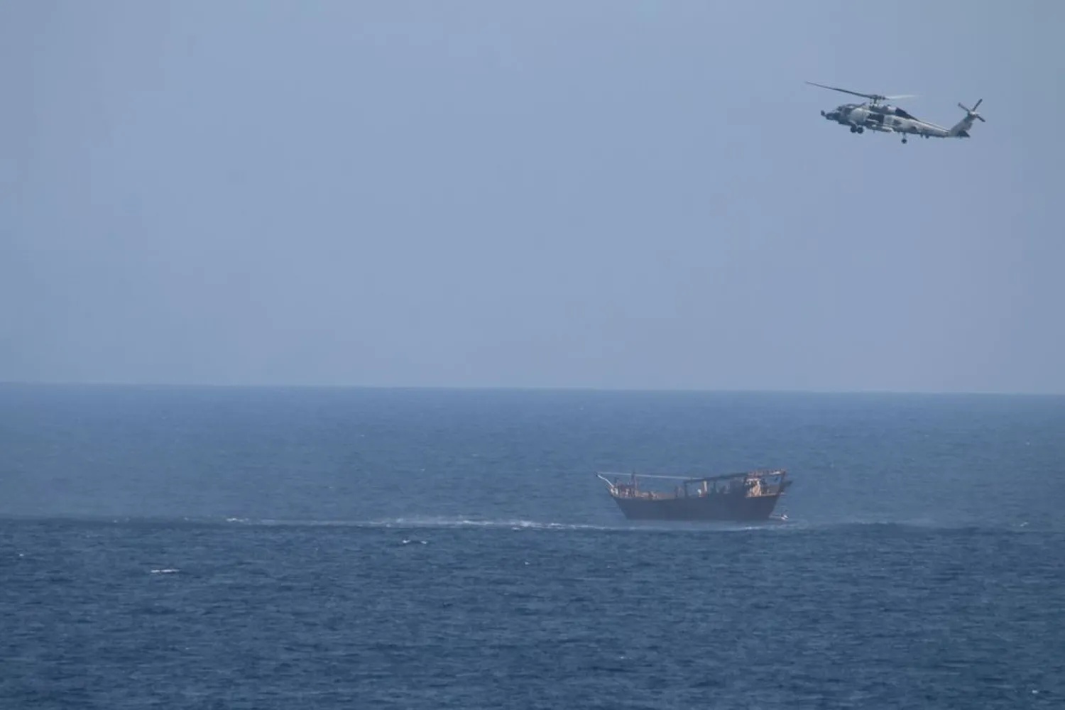 An SH-60 Seahawk helicopter assigned to the United States guided-missile cruiser USS Monterey (CG 61)(not shown) flies above a stateless dhow interdicted with a shipment of illicit weapons in international waters of the North Arabian Sea in this picture taken on May 6, 2021 and released by US Navy on May 9, 2021. US Navy Forces Central Command/US Navy/Handout via REUTERS