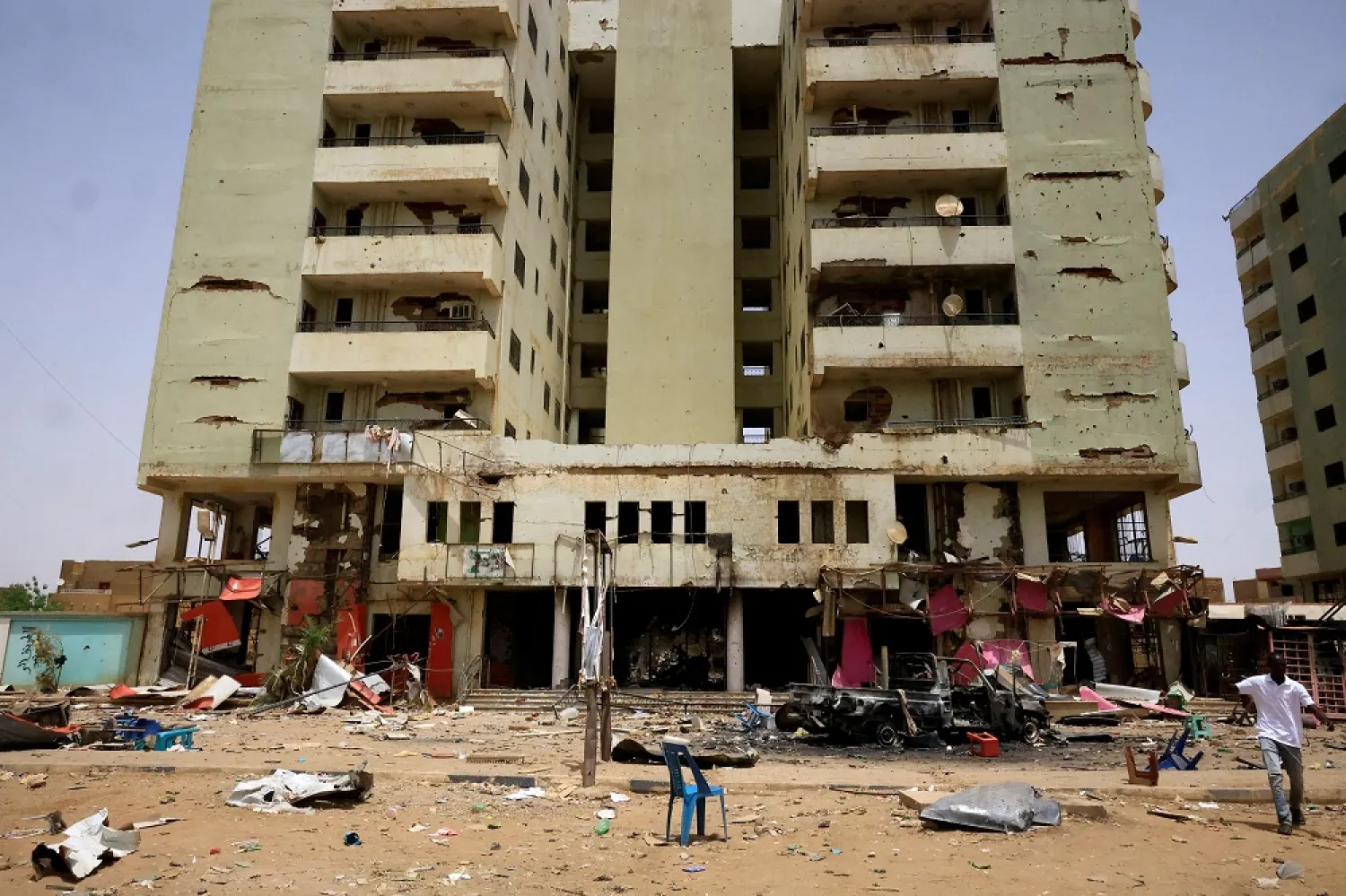 A man walks near a damaged car and buildings at the central market during clashes between the paramilitary Rapid Support Forces and the army in Khartoum North, Sudan April 27, 2023. (Reuters)