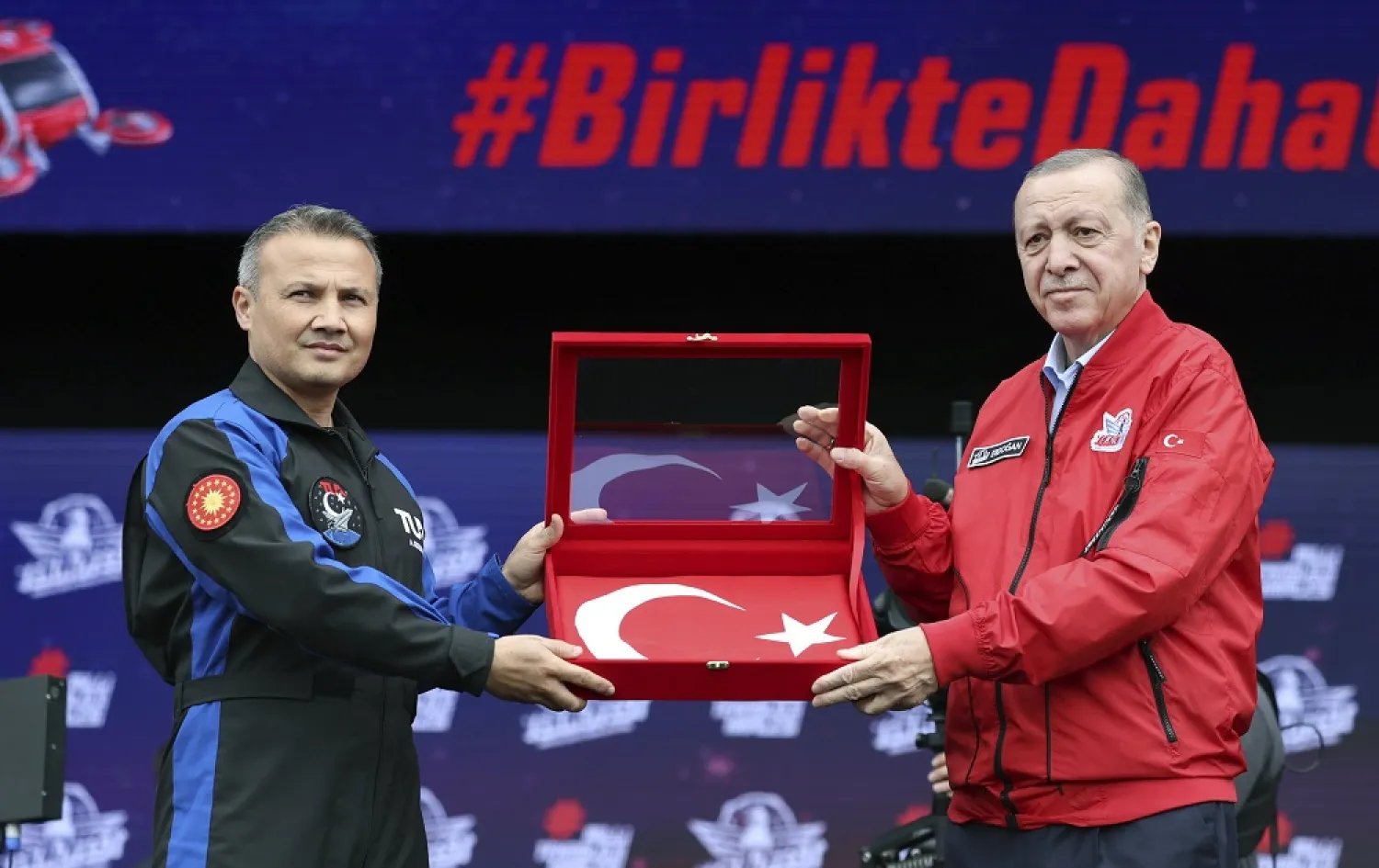 In this photo released by the Turkish Presidency, Türkiye's President Recep Tayyip Erdogan, right, holds a Turkish flag with Turkish air force pilot Alper Gezeravci at Teknofest military fair in Istanbul, Türkiye, Saturday, April 29, 2023. (Turkish Presidency via AP) 