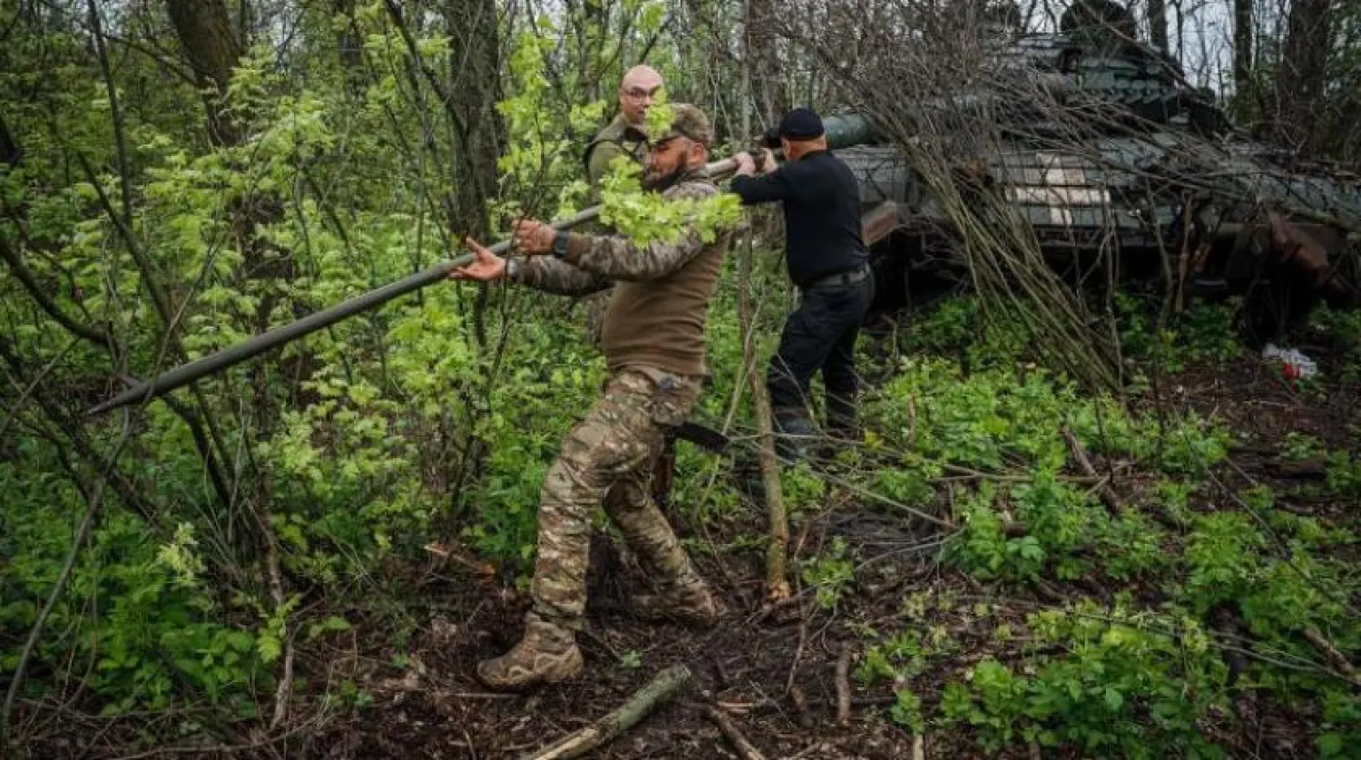 Ukrainian servicemen clean the cannon of their tank on a position near the frontline city of Bakhmut, Donetsk region, on April 29, 2023, amid the Russian invasion of Ukraine. (Photo by Dimitar DILKOFF / AFP)