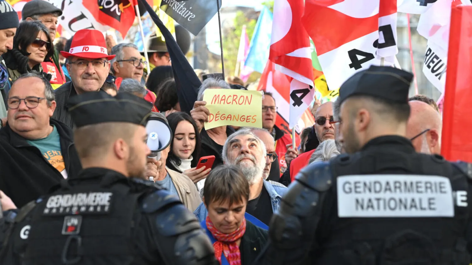 A protester holds a sign that reads, 'Macron Leave', as they wait for the arrival of the French president a month after his government pushed an unpopular pensions reform act through parliament, in Ganges, southern France on April 20, 2023. Sylvain Thomas, AFP
