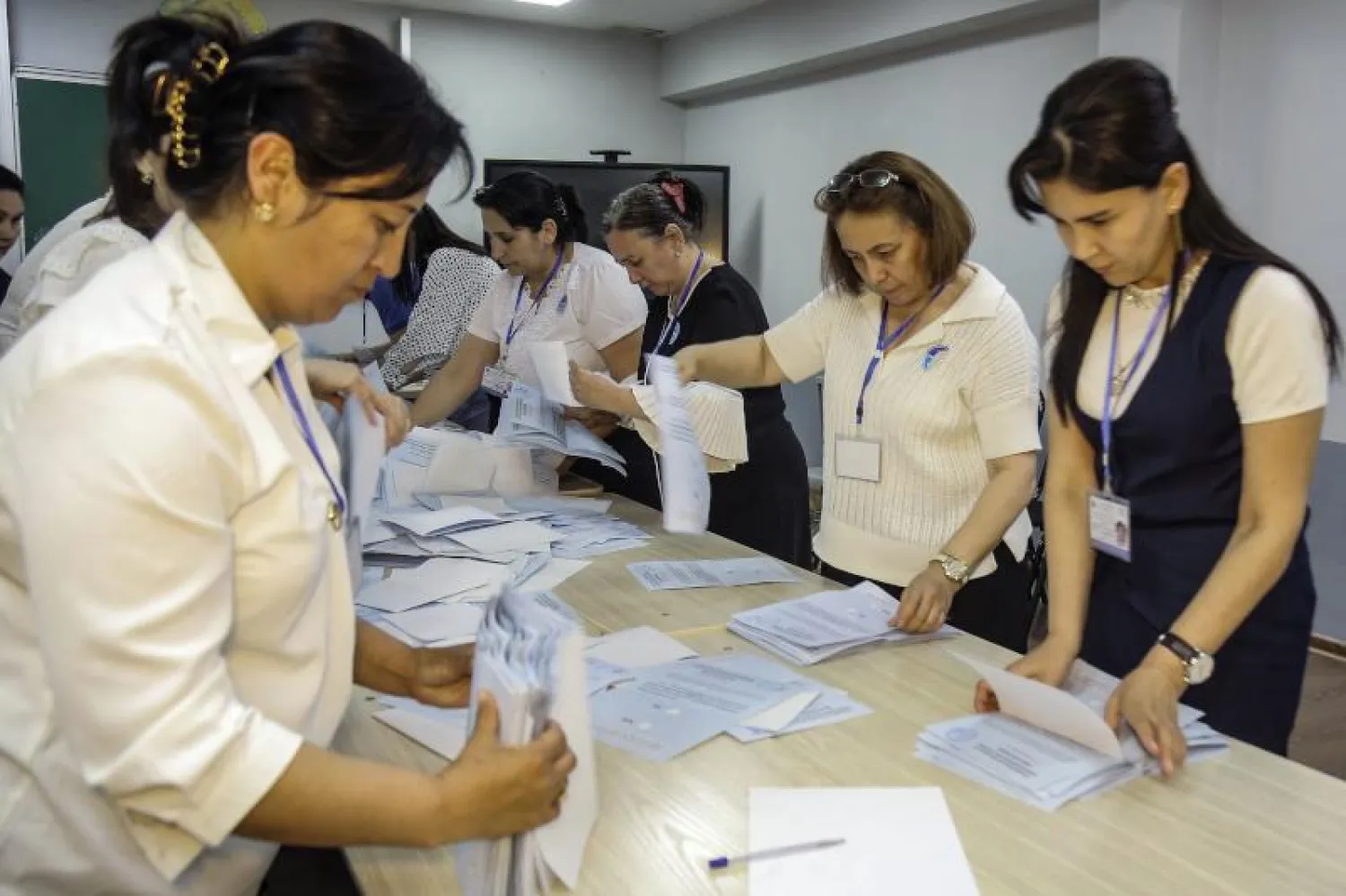 أعضاء لجنة انتخابية محلية يفرزون الأصوات بمركز اقتراع في طشقند (أ.ف.ب)