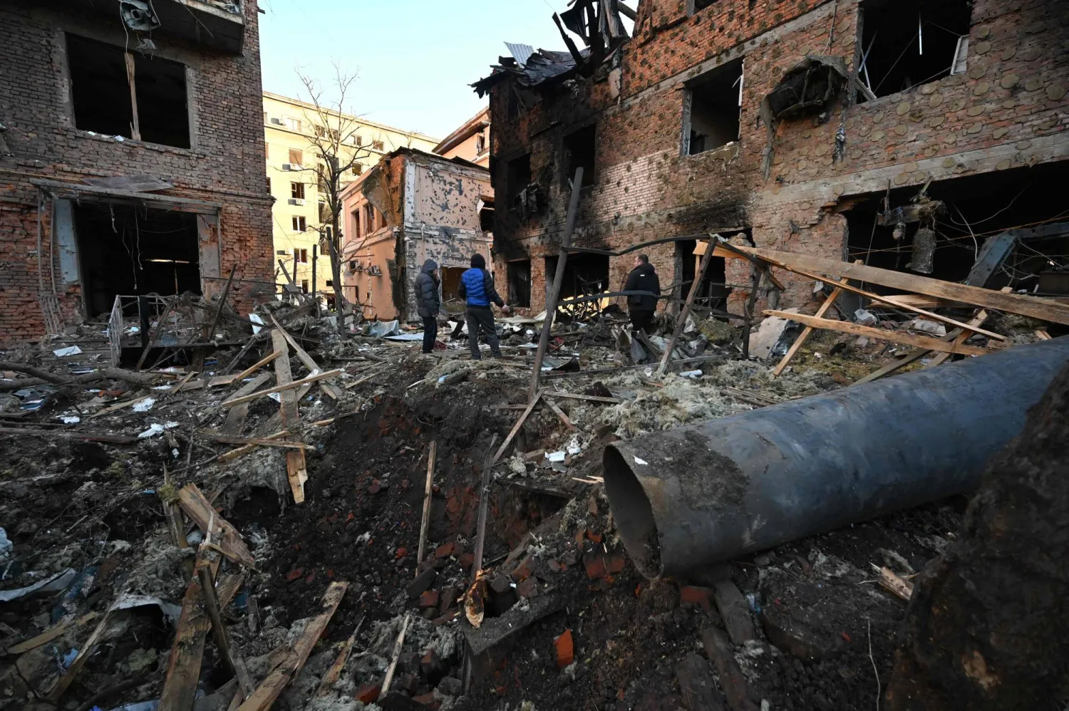 Local residents inspect damages outside an apartment building after the overnight Russian drones attack in Kharkiv, December 31, 2023. (Photo by SERGEY BOBOK / AFP)