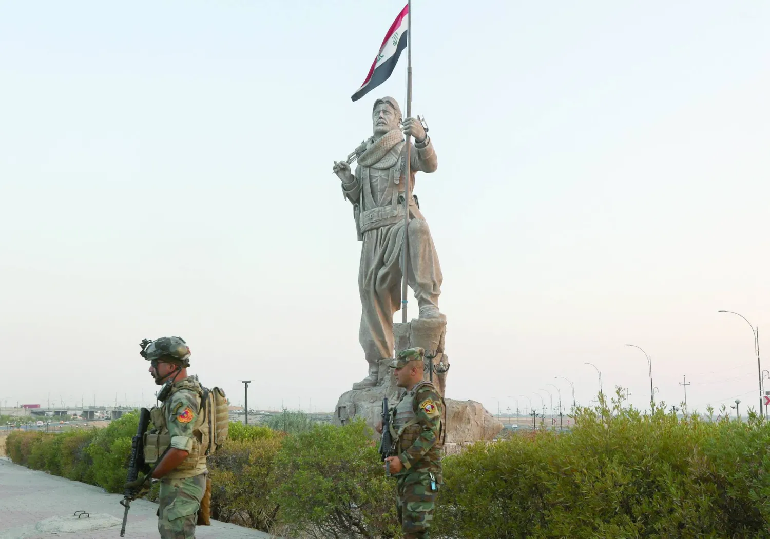 قوات الأمن العراقية تقف بالقرب من تمثال البيشمركة في كركوك في 5 سبتمبر الماضي (رويترز)