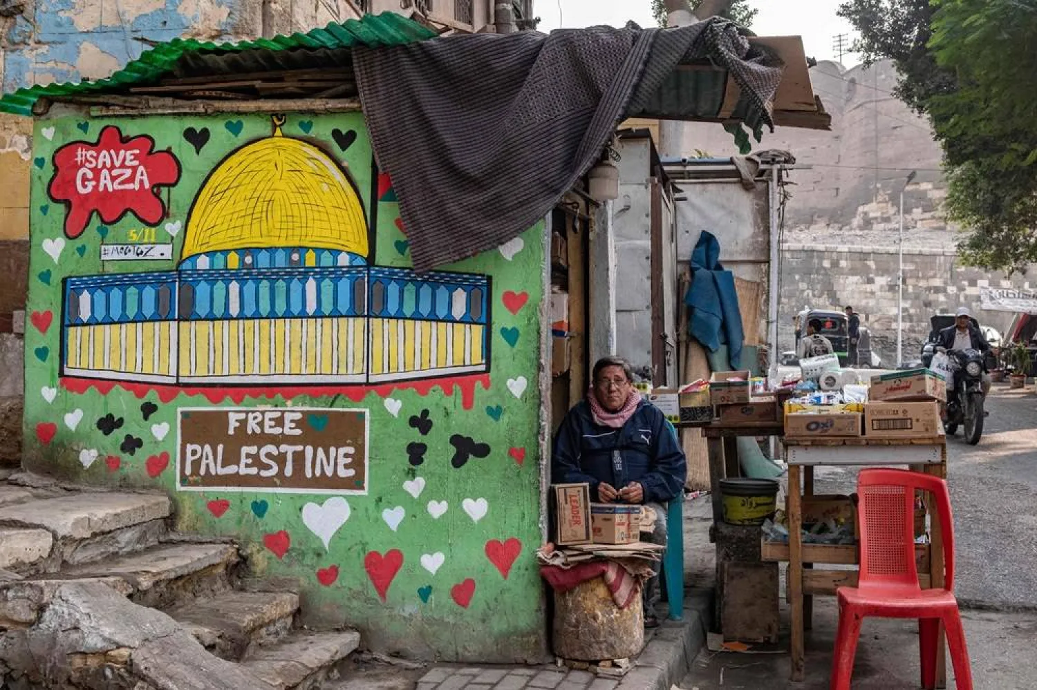 A shopkeeper waits for customers in his stall adorned with graffiti supporting Palestinians in al-Darb al-Ahmar district in Cairo on December 4, 2023. (AFP)