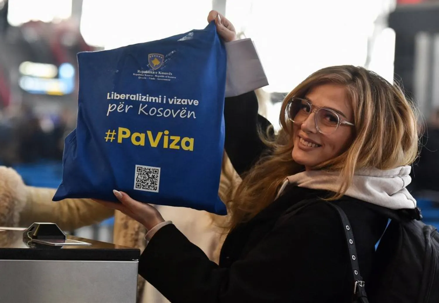 A passenger holds a tote bag with a sign that reads "#WithoutVisa" as Kosovo citizens start to travel to Schengen area without a visa for the first time, at Pristina Airport, near Pristina, Kosovo January 1, 2024. (Reuters)