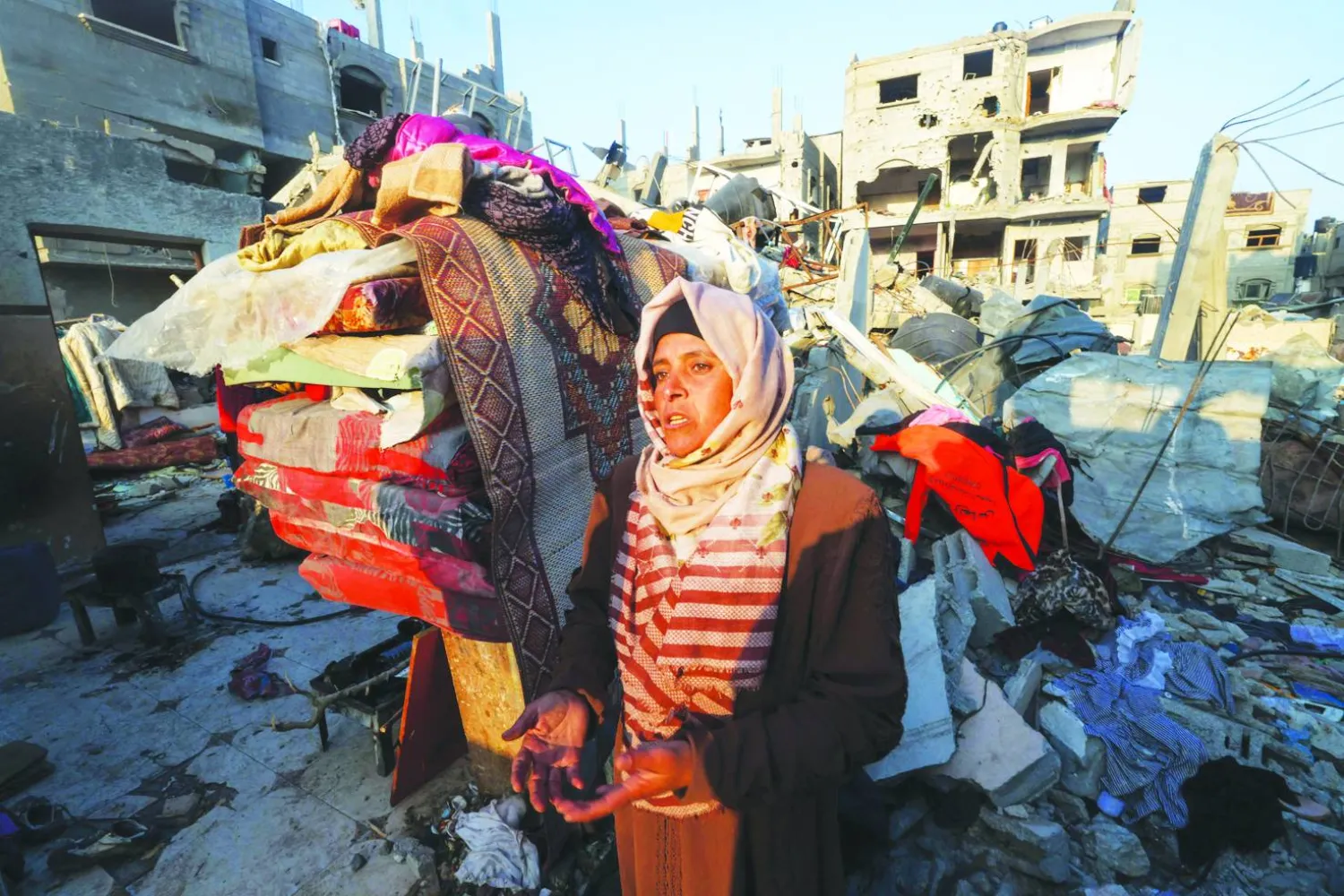  فلسطينية مصدومة وهي تمر أمام منزل دمّره القصف الإسرائيلي في مخيم رفح جنوب قطاع غزة أمس (أ.ف.ب)