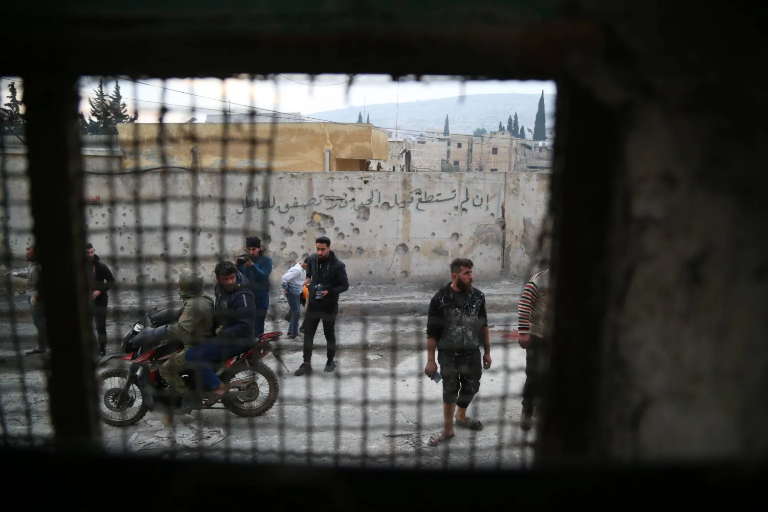 أهالٍ يتفقدون الأماكن المتضررة جراء سقوط قذائف على منطقة سكنية في مدينة دارة عزة بريف حلب (إ.ب.أ)