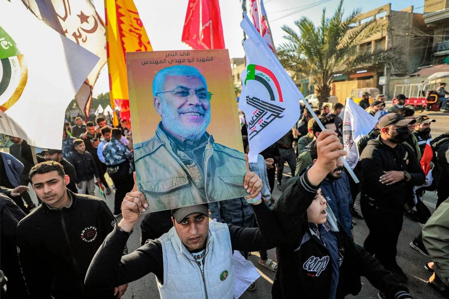 Supporters of Iraqi factions carry a poster of al-Muhandis in Baghdad. (AFP) 