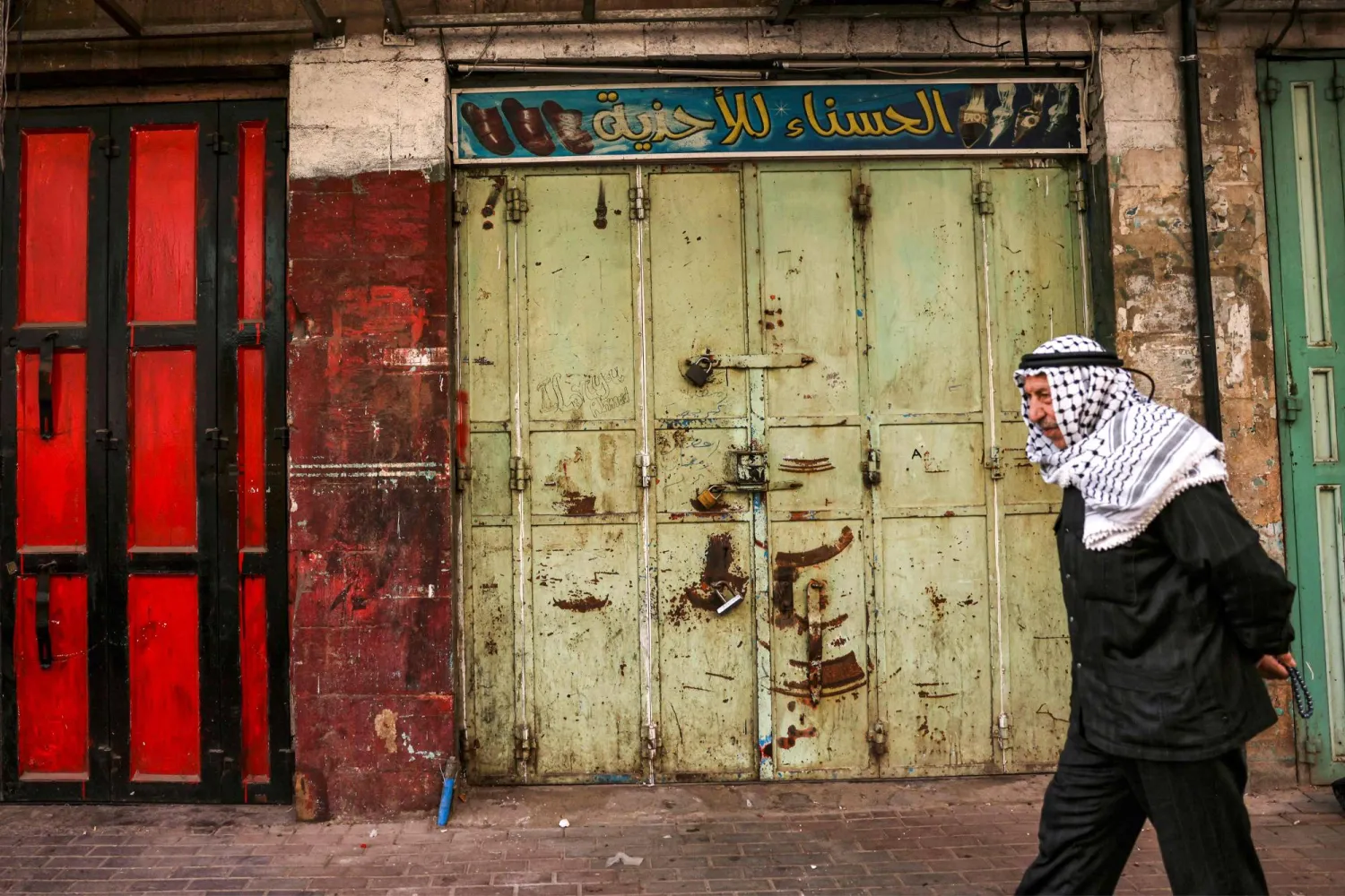 رجل يمر بجانب أحد المحالّ المغلقة في الضفة الغربية اليوم (أ.ف.ب)