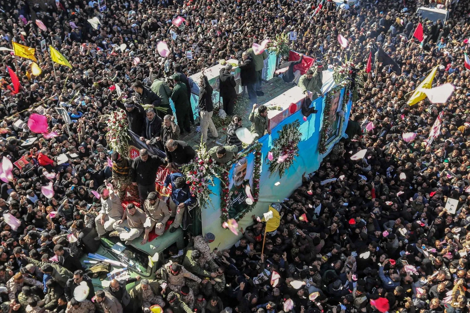 İranlılar, 7 Ocak 2020'de memleketi Kirman'da merhum Kudüs Gücü komutanı Kasım Süleymani'nin cenaze töreni sırasında tabutunu taşıyan bir arabanın etrafında toplanırken (AFP)