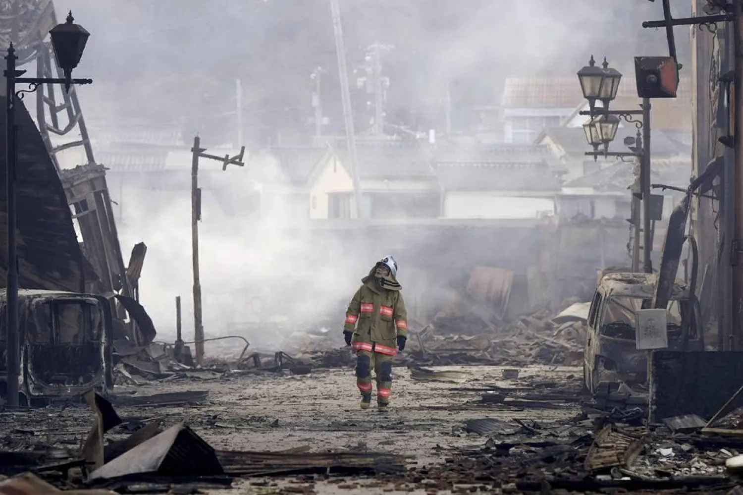  A firefighter walks through the rubble and wreckage of a burned-out marketplace following earthquake in Wajima, Ishikawa prefecture, Japan Tuesday, Jan. 2, 2024. (Kyodo News via AP)