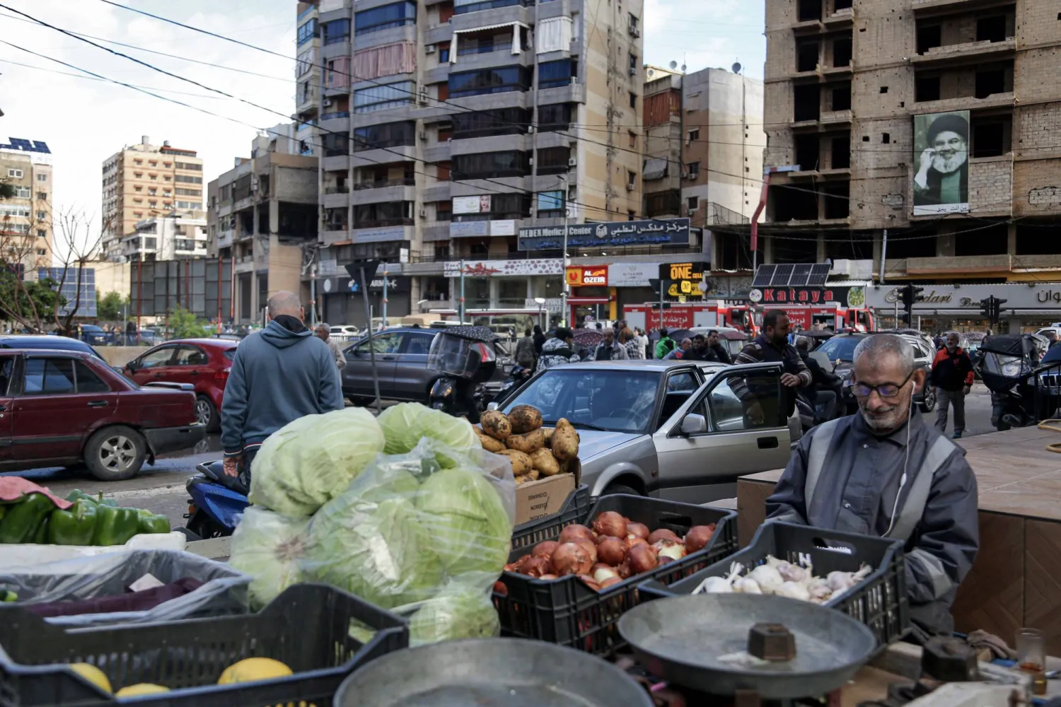 بائع خضراوات ينتظر العملاء خارج المنطقة التي تعرض فيها مكتب «حماس» (أقصى اليسار) لهجوم إسرائيلي أدى إلى مقتل صالح العاروري (د.ب.أ)