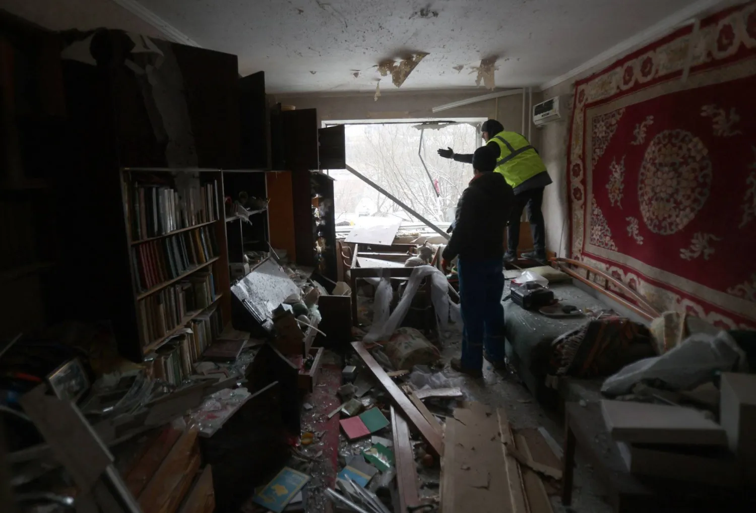 متطوعون يعملون على تغطية زجاج النوافذ المكسور في مبنى شاهق دمر بعد هجوم صاروخي روسي في وسط كييف (أ.ف.ب)