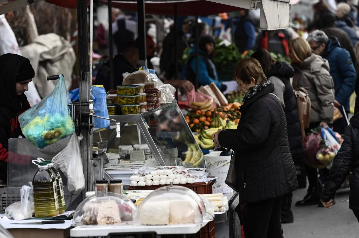 سيدة تشتري الجبن في إحدى الأسواق الشعبية بمدينة سالونيكي اليونانية (أ.ف.ب)