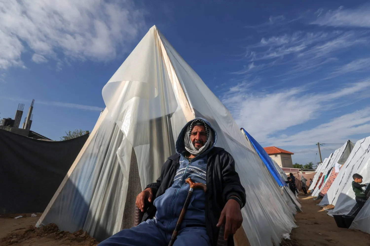 نازح فلسطيني يجلس أمام خيمة من الخشب والمشمع في رفح جنوب قطاع غزة (رويترز) 