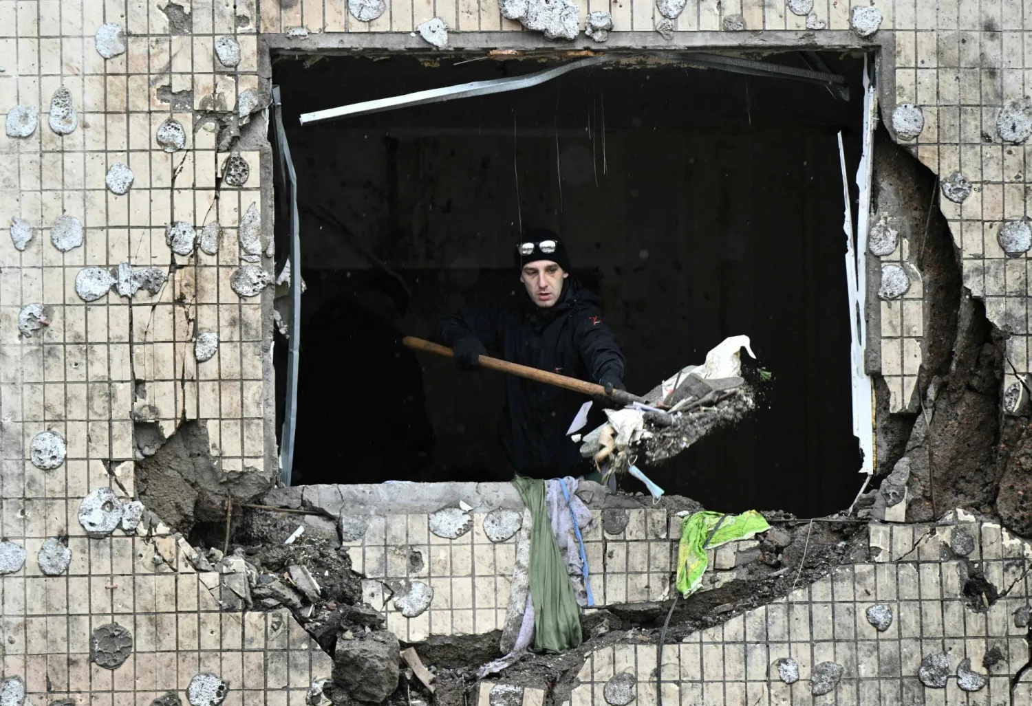 A local resident clears debris from an apartment at a heavily damaged residential building, three days after a Russian missile attack in Kyiv, on January 5, 2024, amid the Russian invasion of Ukraine. (Photo by Genya SAVILOV / AFP)