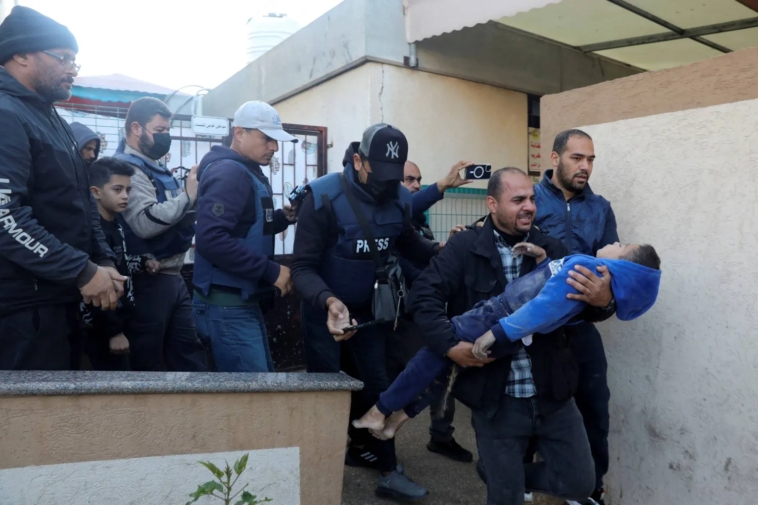 مراسل قناة "االحدث" محمد عوض يحمل مصدوما جثة إبن أخيه الذي قتلت عائلته بأكملها في قصف إسرائيلي على المستشفى الأوروبي في خان يونس امس (رويترز) 