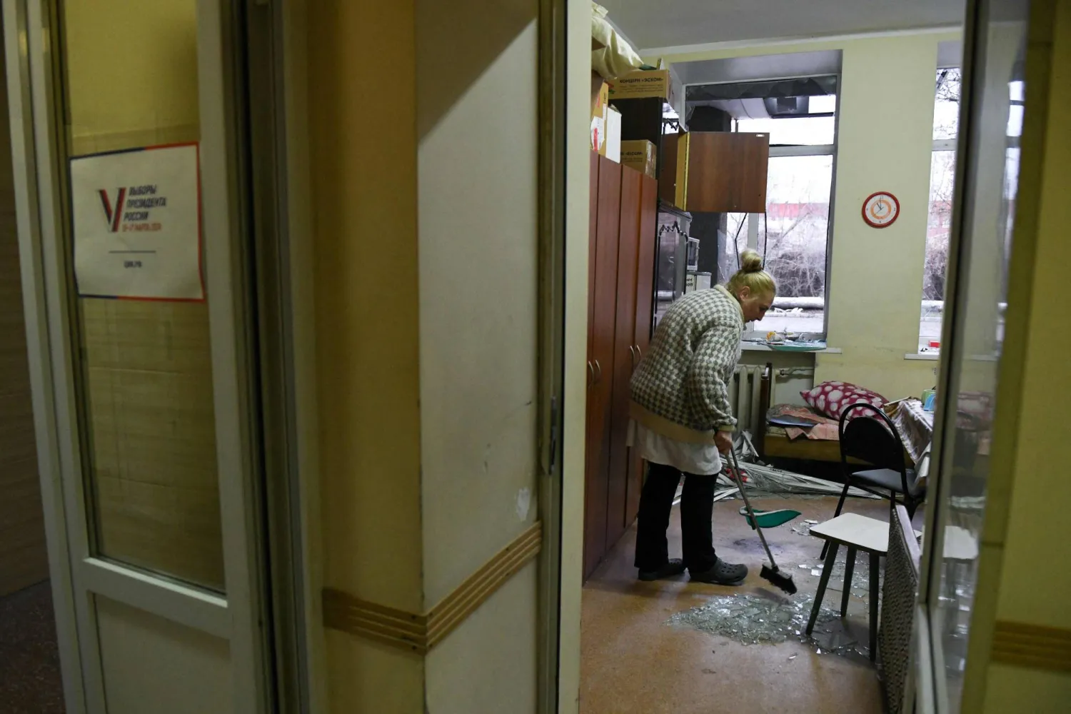 امرأة تزيل الزجاج المهشم من غرفة داخل مستشفى طاله القصف في دونيتسك الأحد (أ.ف.ب)