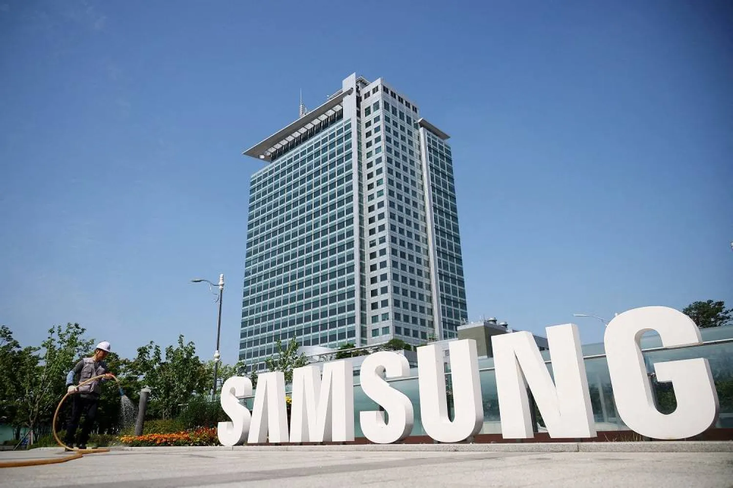 A worker waters a flower bed next to the logo of Samsung Electronics during a media tour at Samsung Electronics' headquarters in Suwon, South Korea, June 13, 2023. (Reuters)