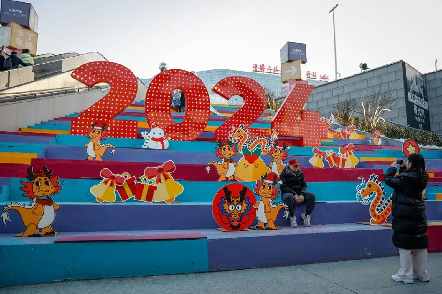 People pose for photographs at a 2024 New Year's signage at a shopping district in Beijing, China, 05 January 2024. (EPA)