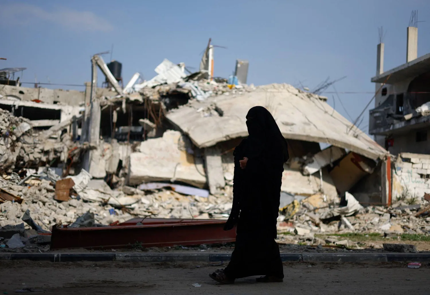 A Palestinian woman walks near the rubble of a house destroyed in an Israeli strike amid the ongoing conflict between Israel and the Palestinian group Hamas, in Rafah in the southern Gaza Strip, January 9, 2024. REUTERS/Mohammed Salem