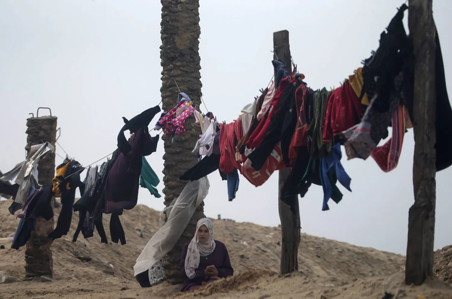نازحون فلسطينيون فرّوا من الحرب يضعون ملابسهم للتجفيف في الهواء بمدينة دير البلح بقطاع غزة (إ.ب.أ)