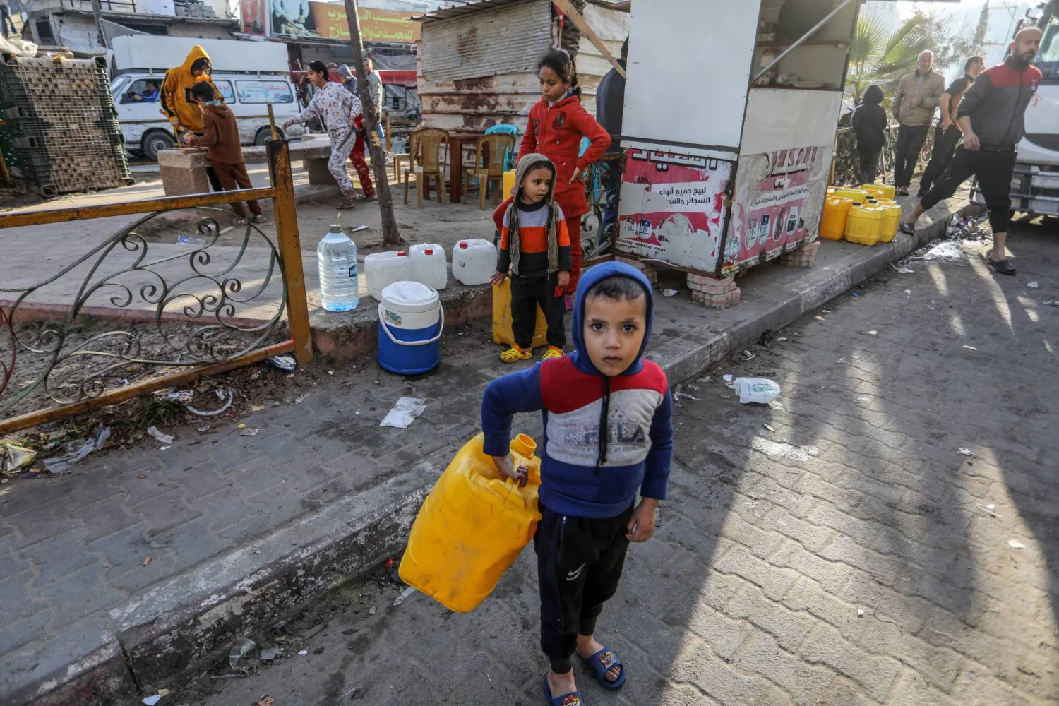 طفل فلسطيني يحمل جرة لملئها بالماء حيث تقوم المنظمات الخيرية بتوزيع المياه على المتضررين من الحرب في غزة (د.ب.أ)