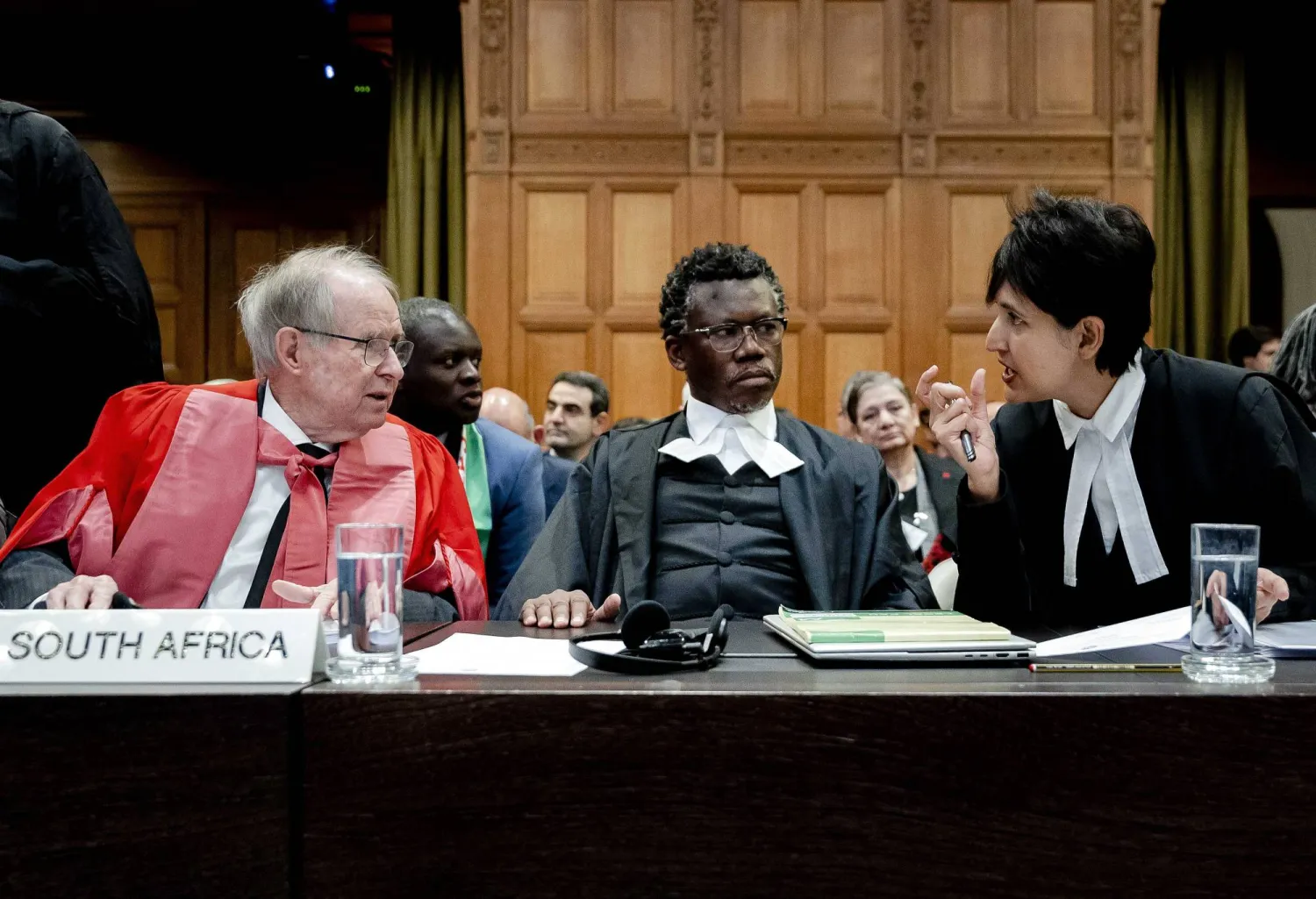 جون دوغارد، أستاذ القانون الدولي، والمحامي تمبيكا نكوكايتوبي، والمحامية عادلة هاشم، يجلسون قبل جلسة الاستماع في قضية الإبادة الجماعية ضد إسرائيل التي رفعتها جنوب أفريقيا، في محكمة العدل الدولية في لاهاي (إ.ب.أ)
