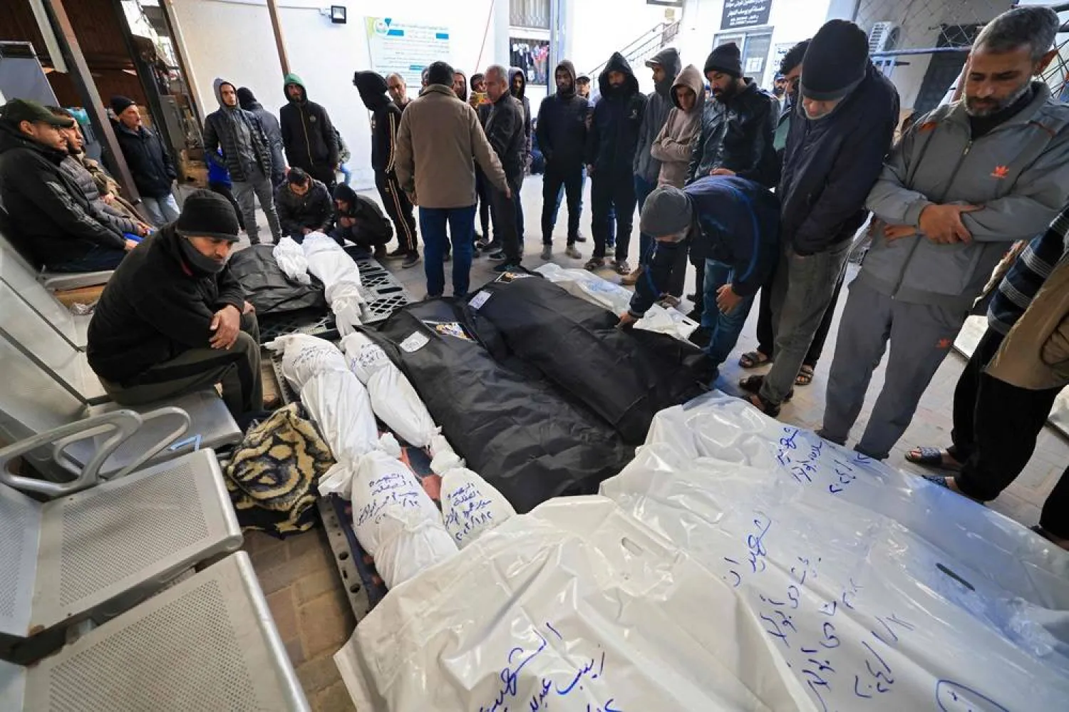People mourn over the shrouded bodies of loved ones killed during Israeli bombardment on January 13, 2024, at the yard of Al-Najjar hospital in Rafah in the southern Gaza Strip amid ongoing battles between Israel and the Palestinian militant group Hamas. (AFP)