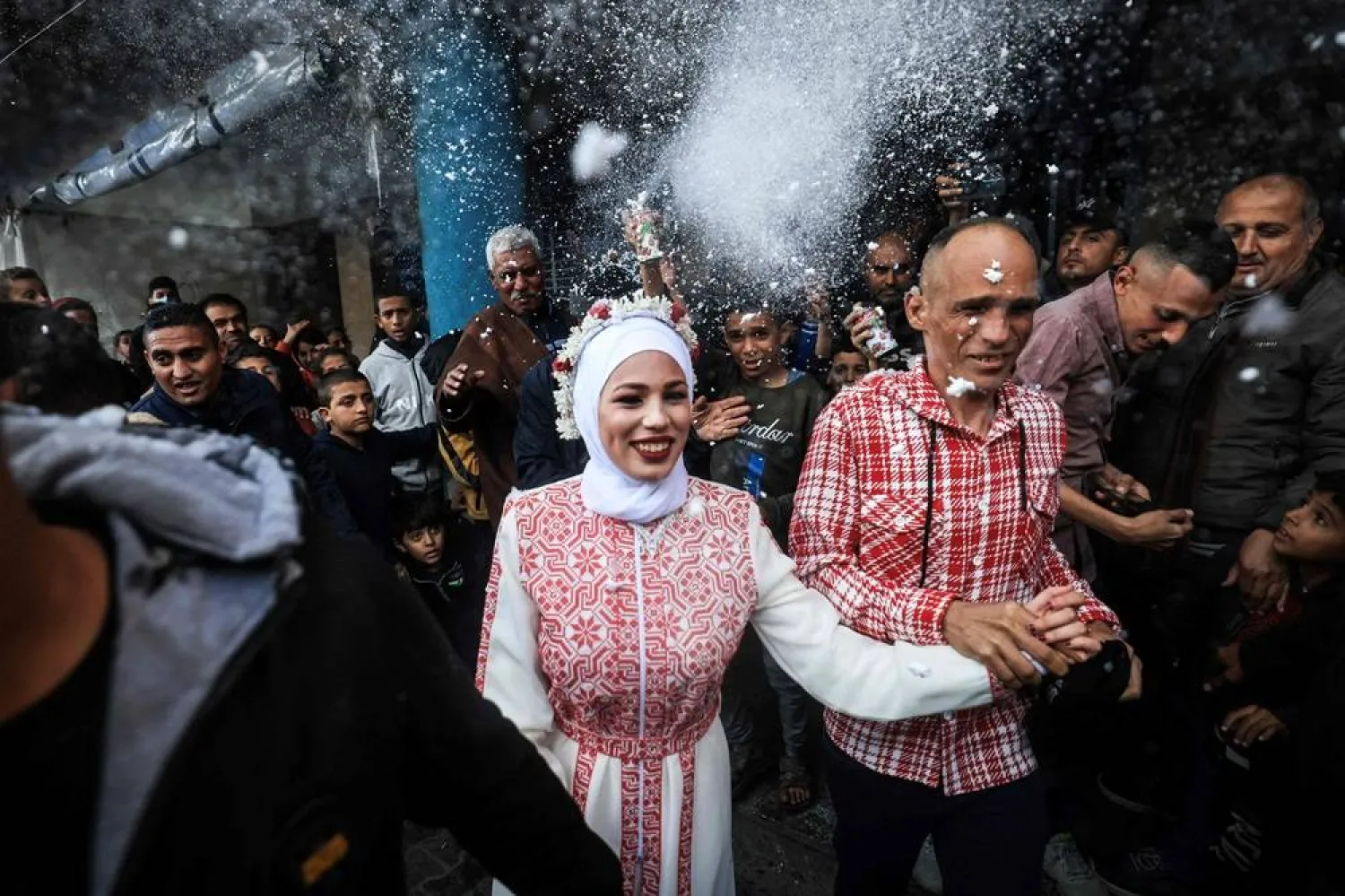 Palestinian bride Afnan Jibril (C) is escorted by her father (C-R) during her wedding at the UNRWA School in the al-Salam neighborhood of Rafah, southern Gaza Strip, on January 12, 2024, amid continuing battles between Israel and the militant group Hamas. (AFP)