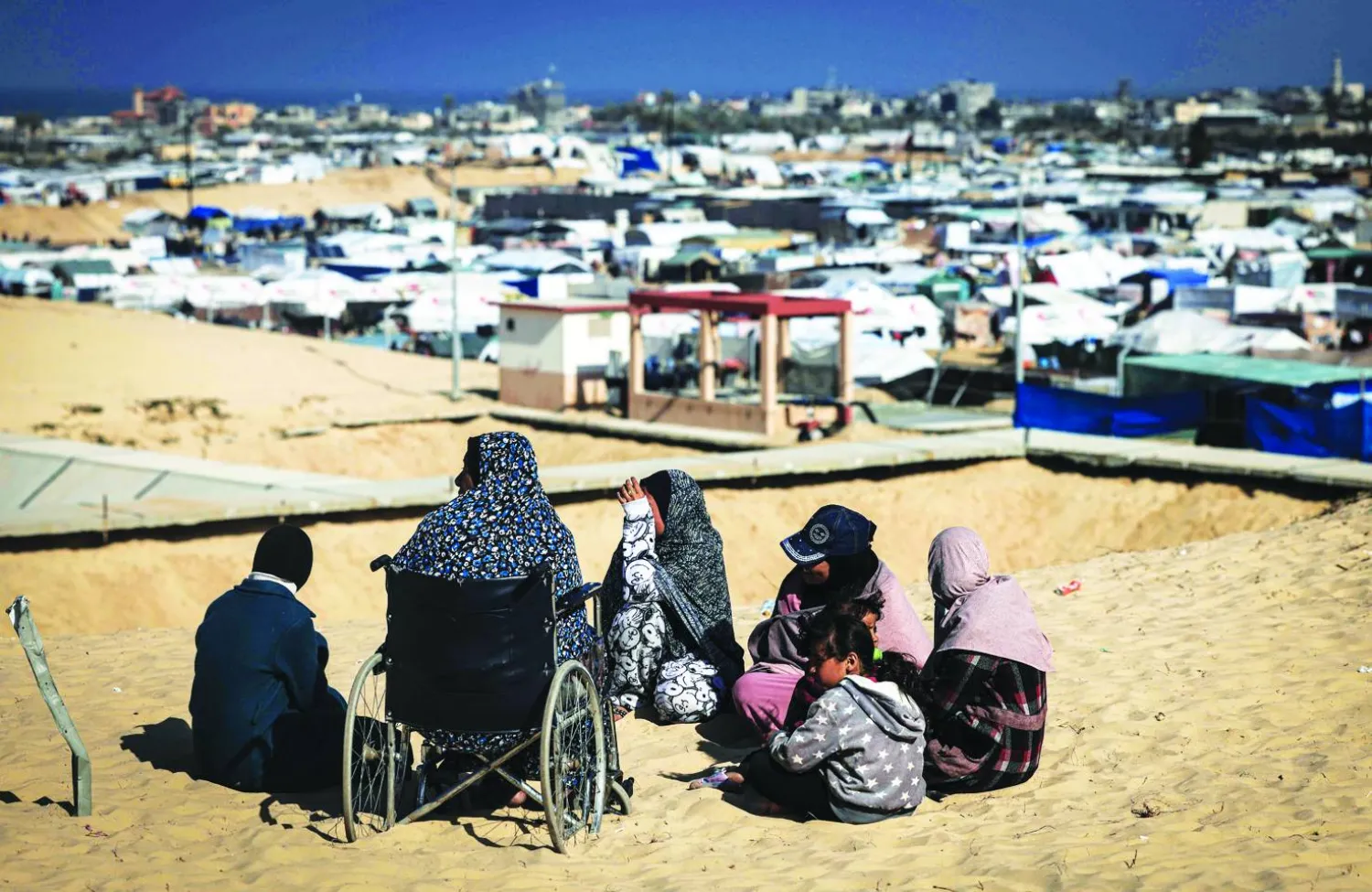
فلسطينيات شرّدتهن الحرب يطللن على مخيم للنازحين غرب رفح جنوب قطاع غزة على الحدود مع مصر أمس (أ.ف.ب)