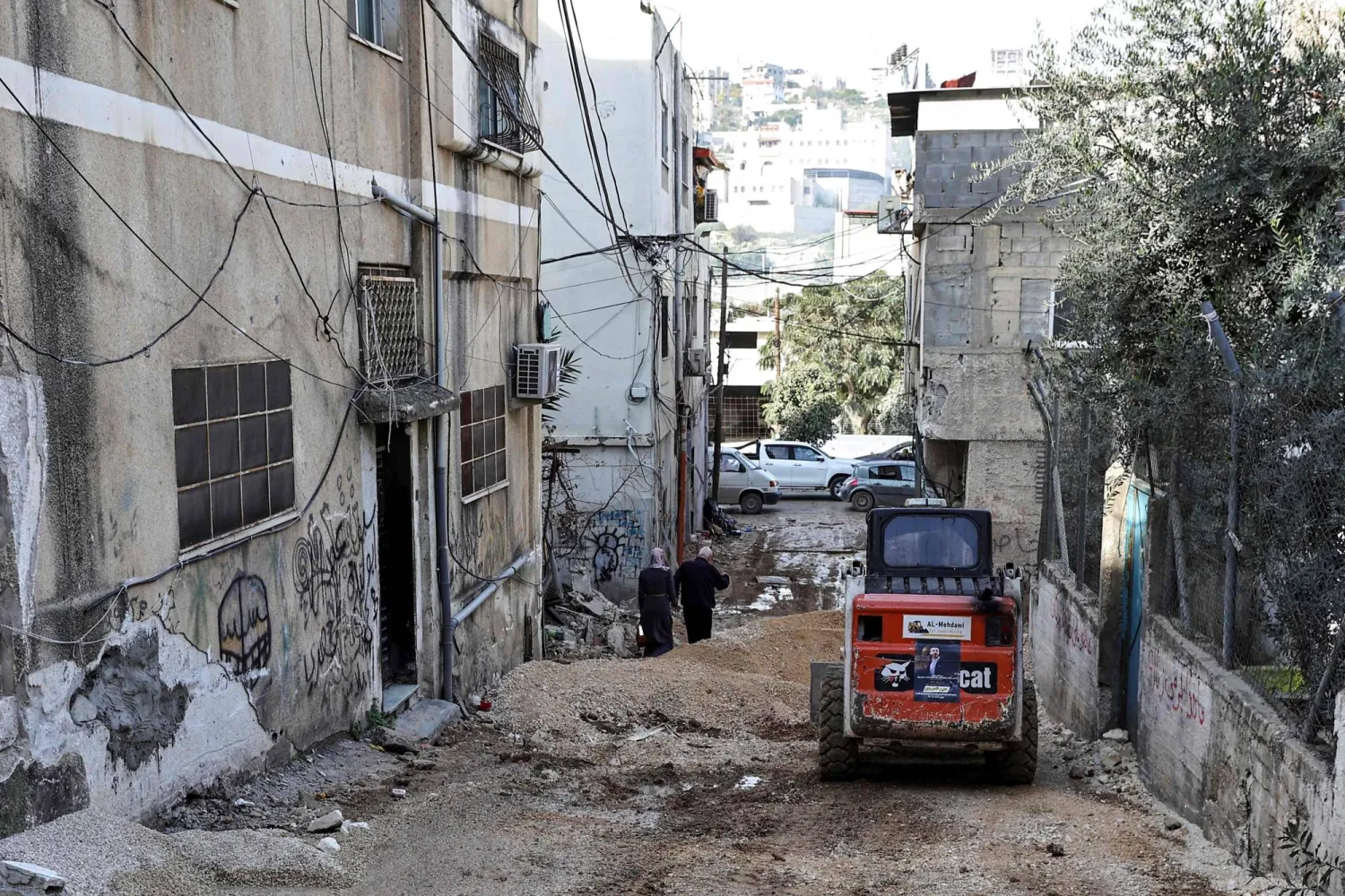 فلسطينيات في أحد شوارع مخيم نور شمس للاجئين حيث شنت غارات إسرائيلية بالقرب من مدينة طولكرم بالضفة الغربية (أ.ف.ب)