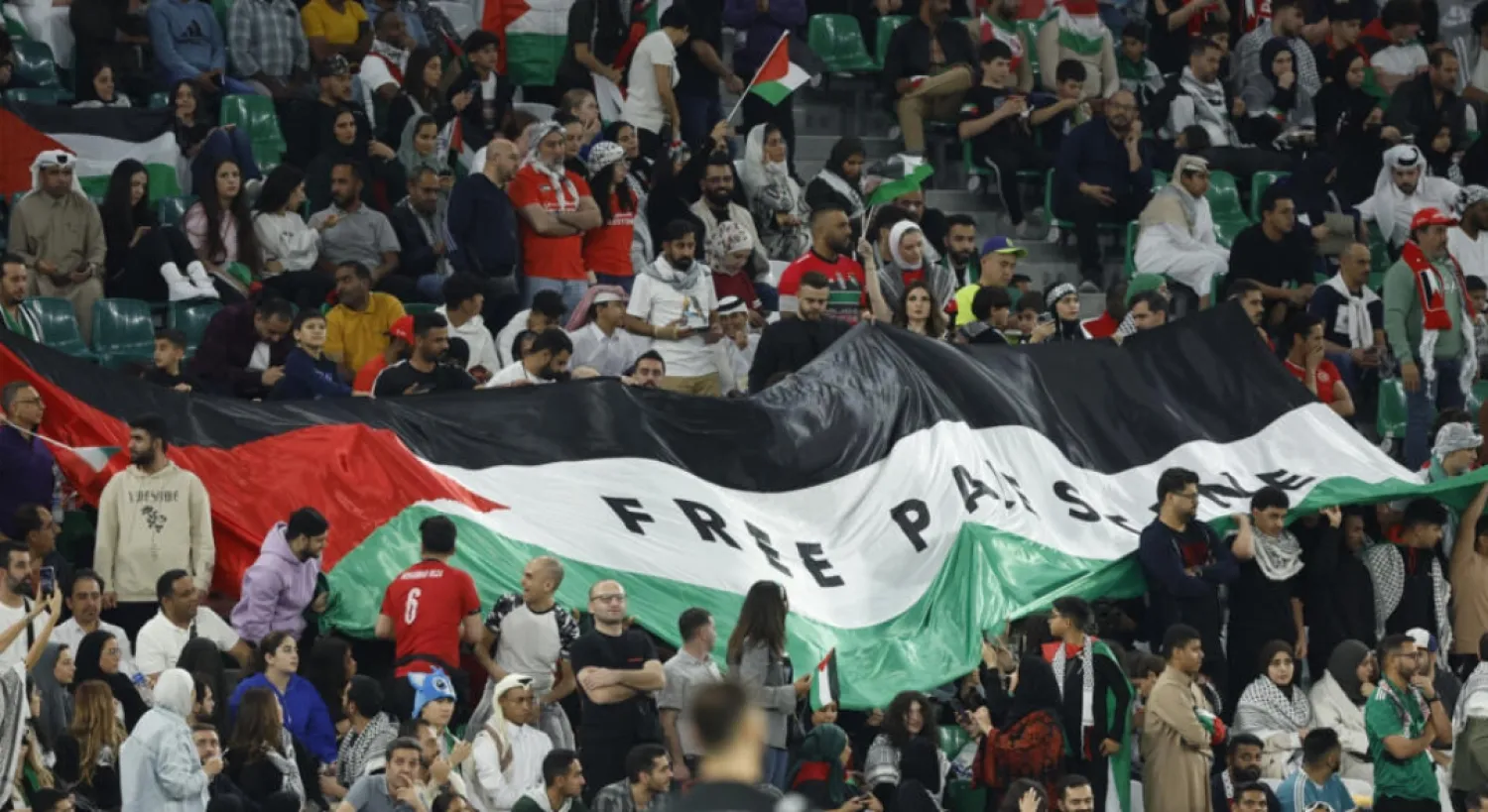 Football fans unfurl a giant Palestinian flag emblazoned with the slogan 'Free Palestine' in the stands during the Qatar 2023 AFC Asian Cup Group C football match between Iran and Palestine © KARIM JAAFAR / AFP
